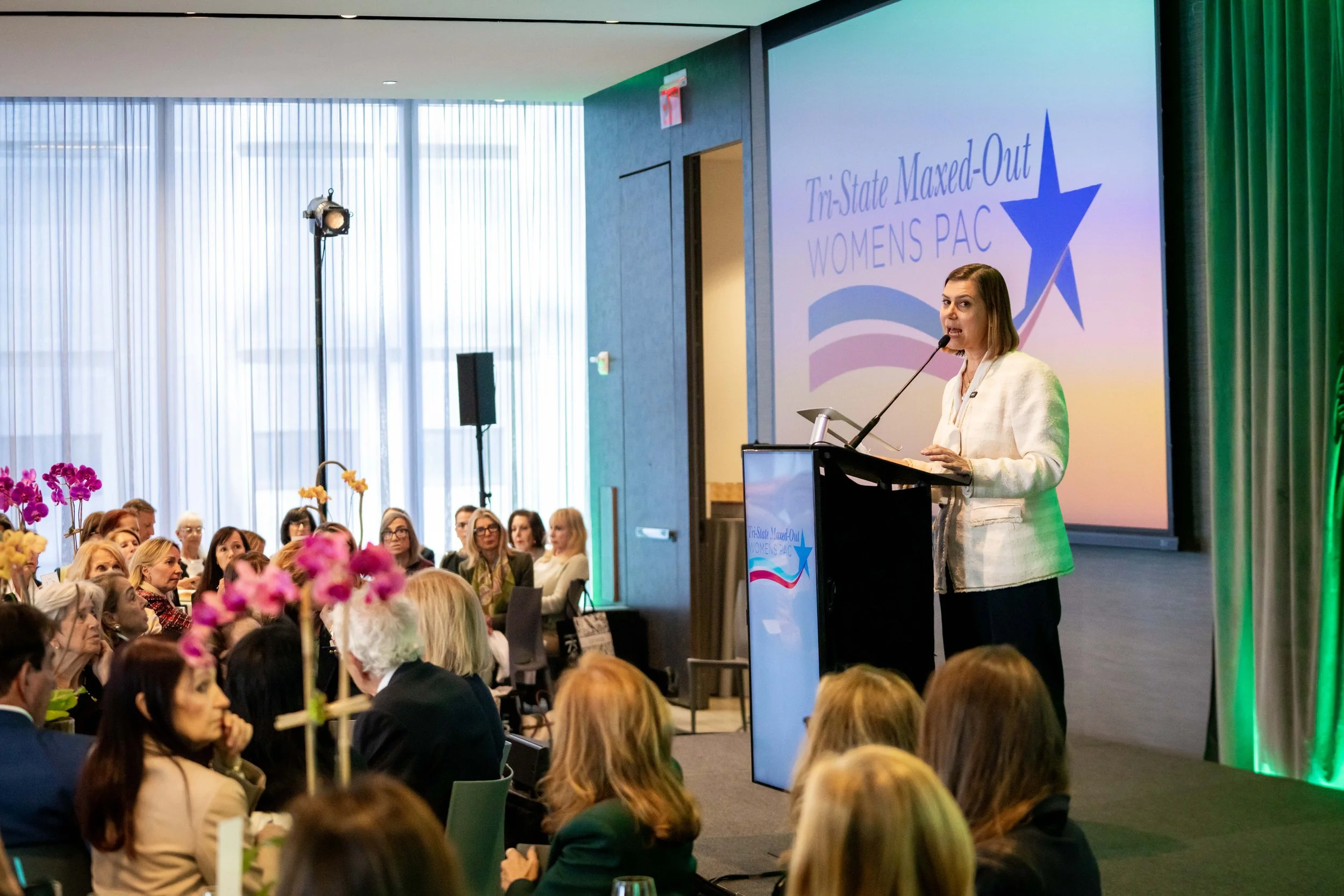 Woman speaking at a podium during the Tri-State Maxed-Out Womens PAC Annual Luncheon.