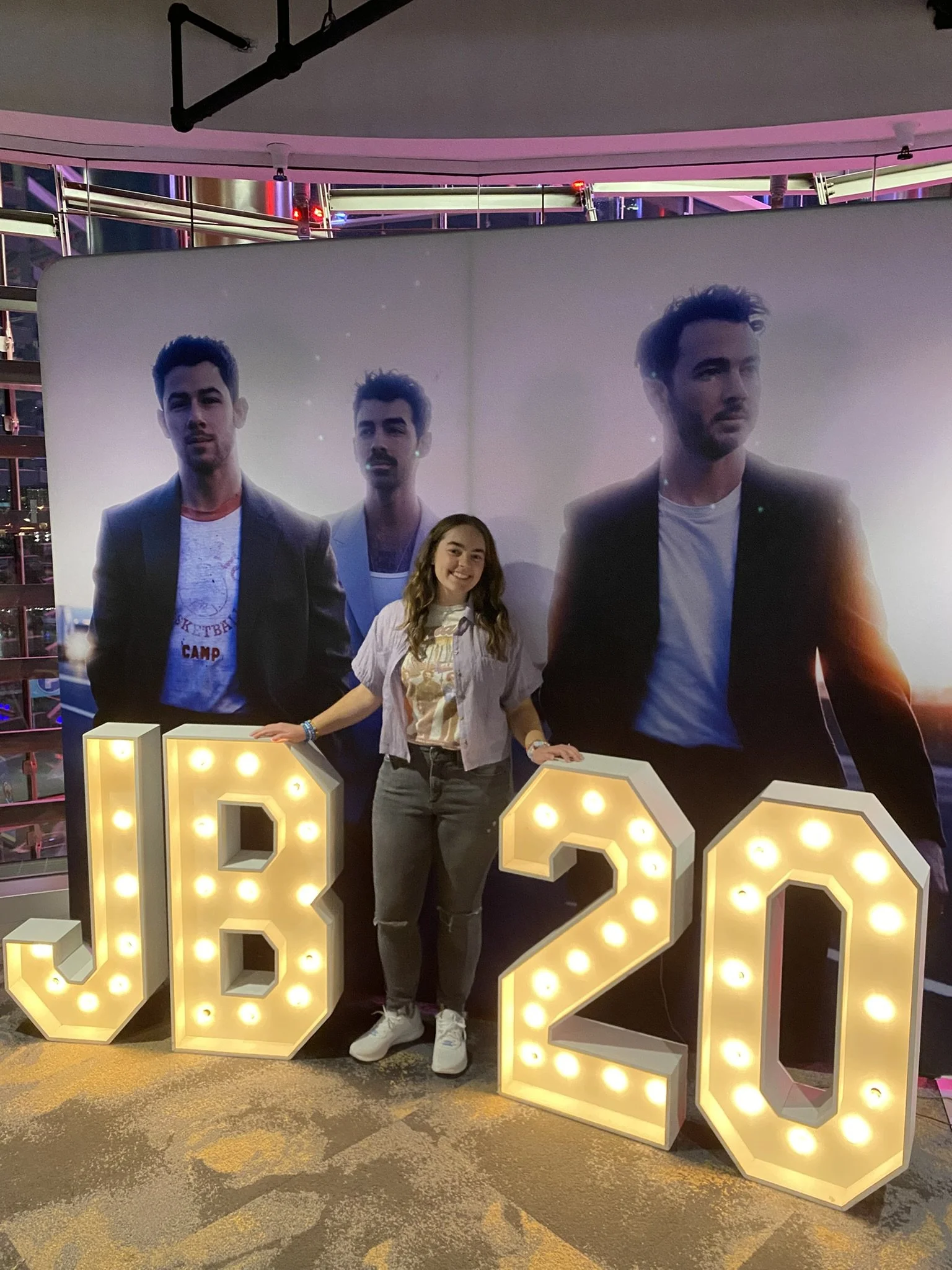 Sarah in front of a Jonas Brothers concert sign