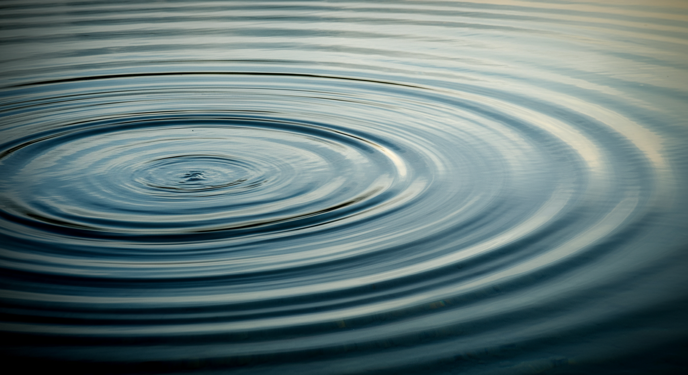 Close-up photo of water ripples on the surface of a body of water, with gentle concentric circles spreading outward.