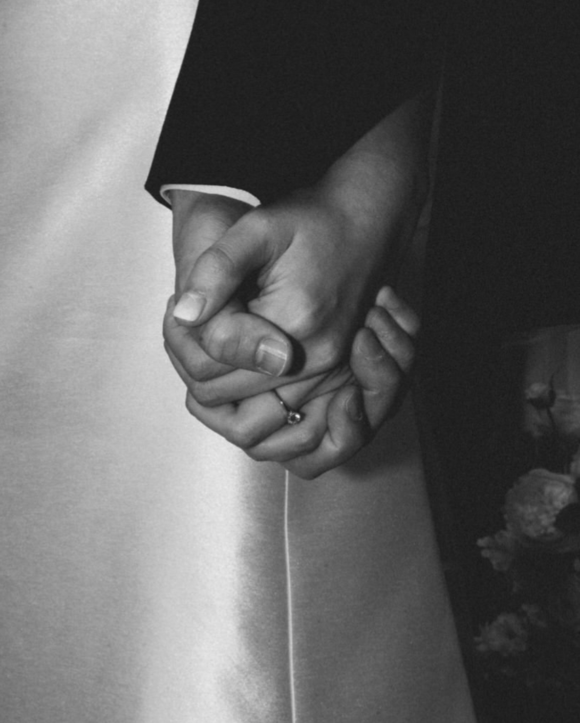 Une photo en noir et blanc montrant deux mains qui tiennent ensemble, avec l'une des mains portant une alliance