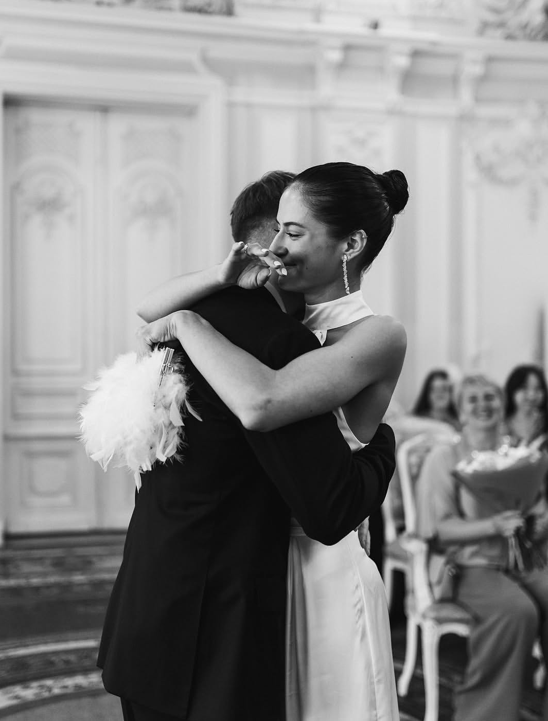 Un couple en train de danser lors d'une cérémonie élégante, en noir et blanc, dans une salle ornée de décorations sophistiquées.