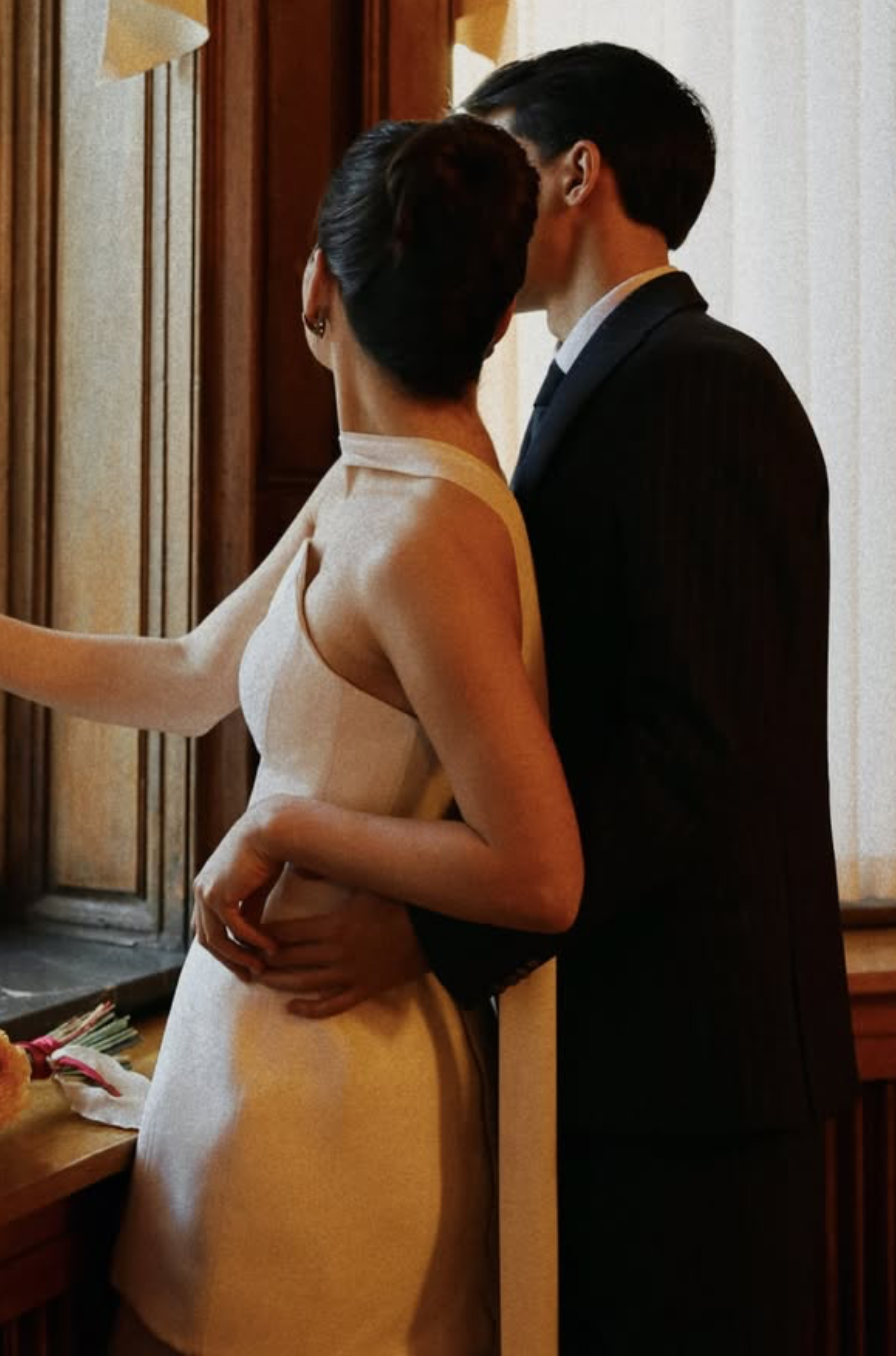 Un couple habillé élégamment partage un moment intime dans une pièce chaleureuse, probablement lors d'une occasion spéciale.