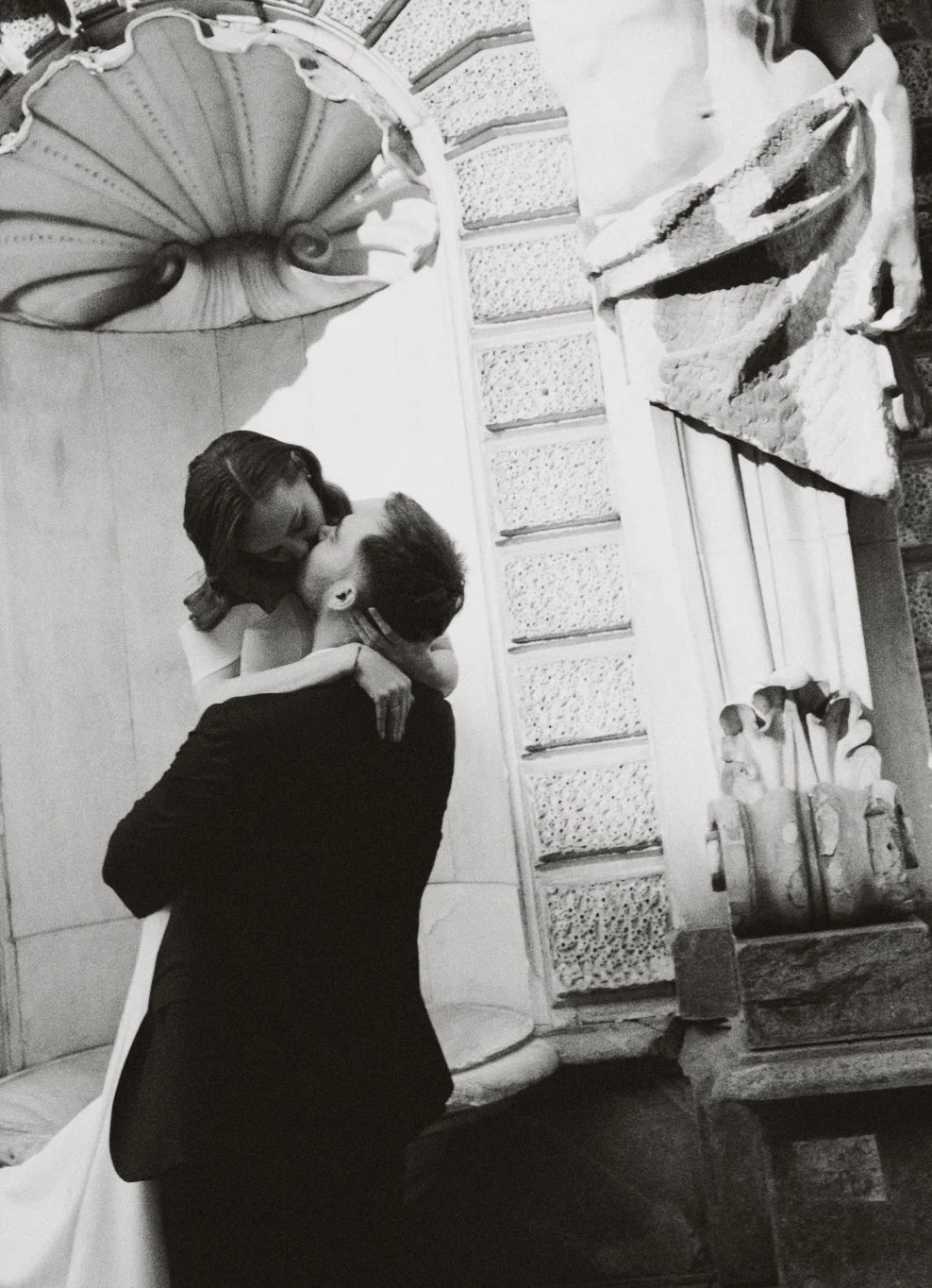 Un couple s'embrassant devant une cheminée en pierre, style vintage, photo en noir et blanc.
