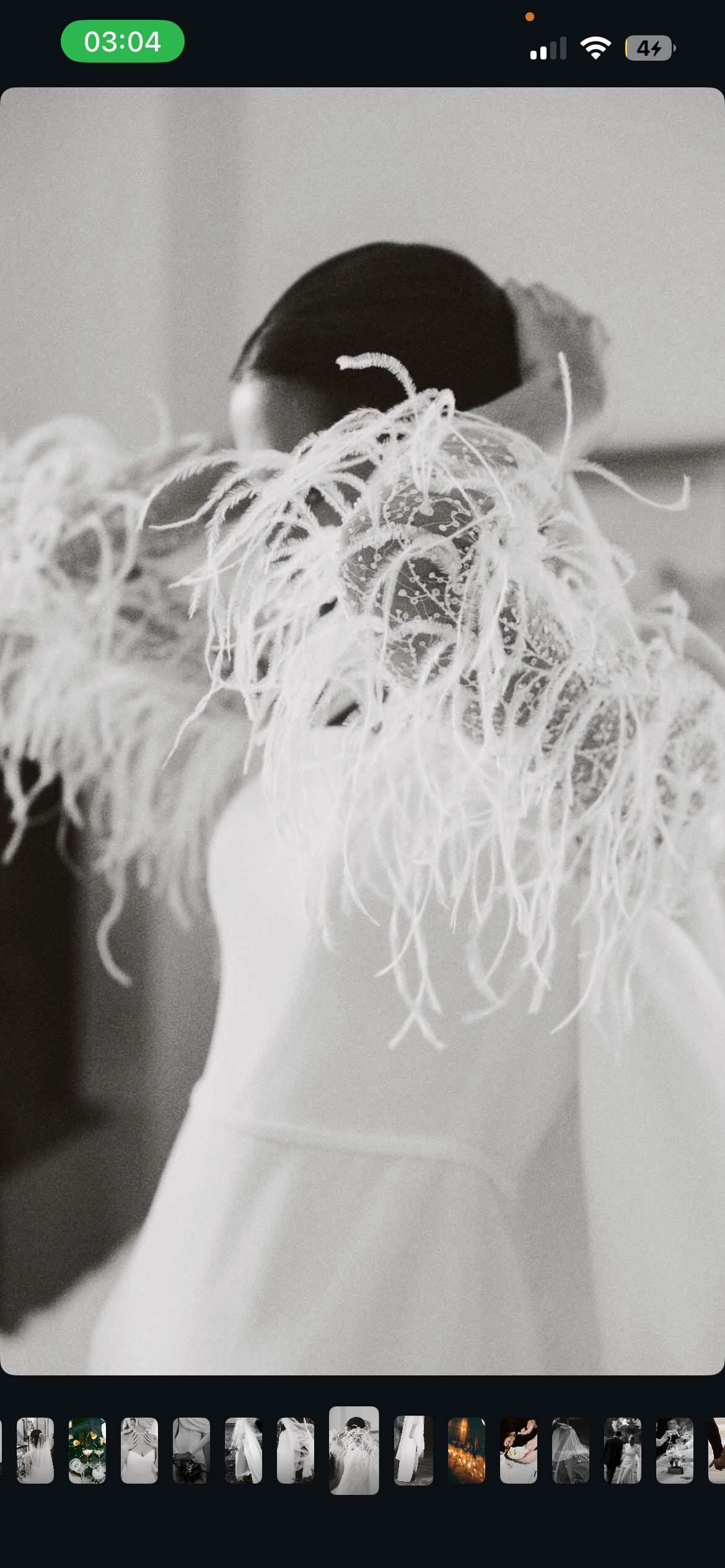 Une personne portant une robe blanche avec un haut décoré de plumes et de motifs organiques en forme de tache.