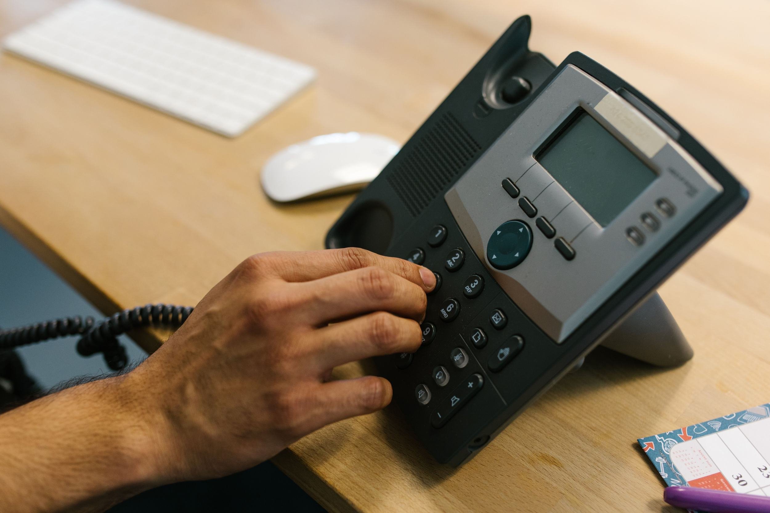 Hand dialing a desk phone in a small business office