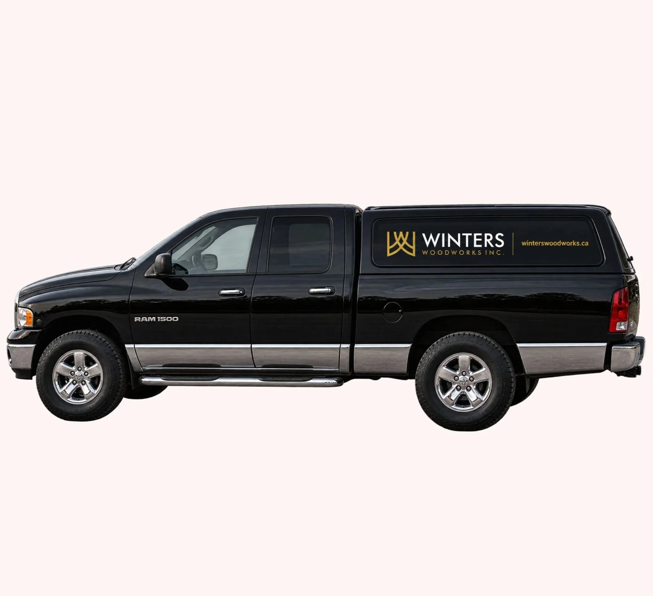 Side view of a black Dodge Ram 1500 pickup truck with signage for Winters Woodworks Inc. on the side, parked on a plain white background.