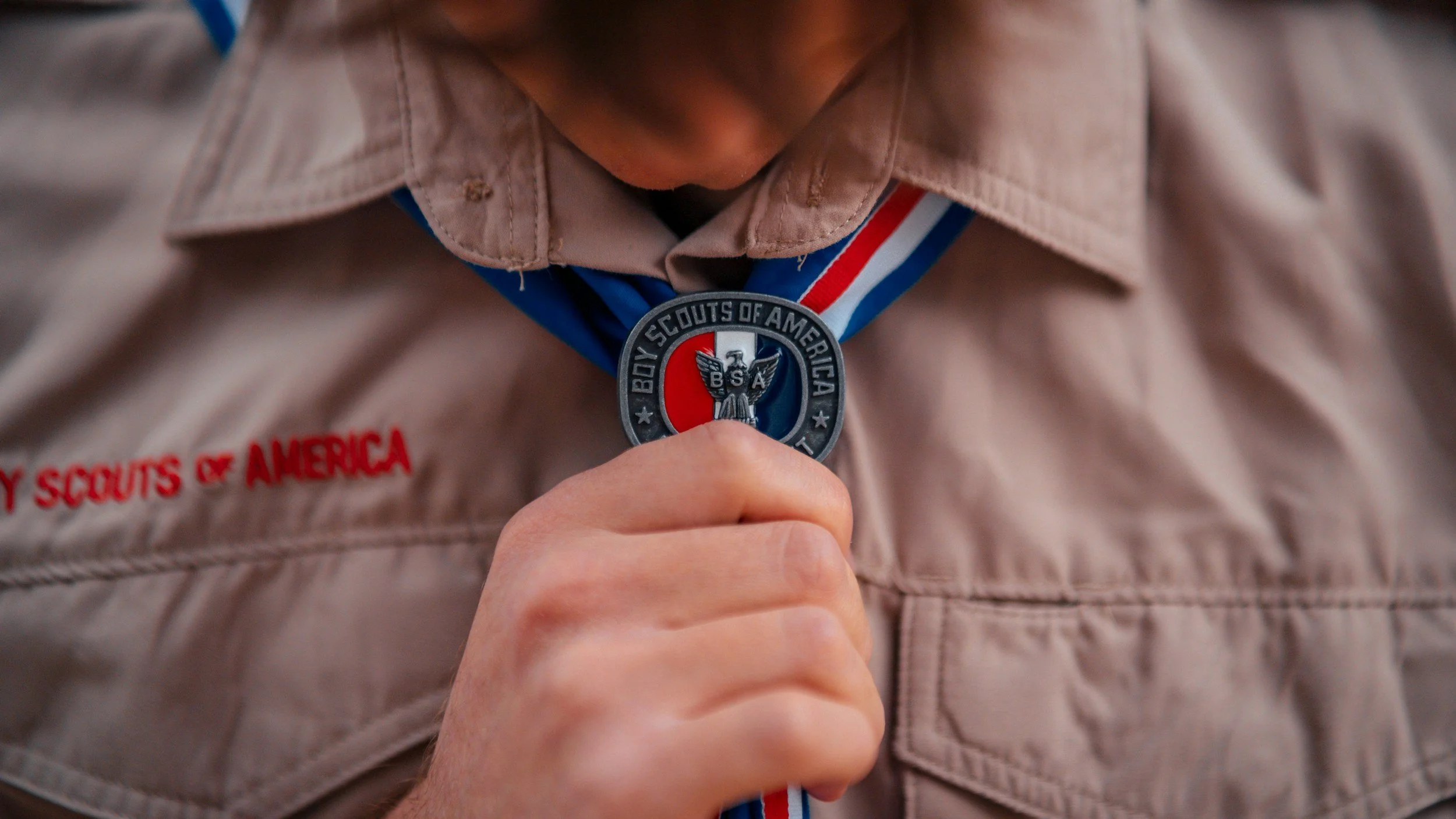 Close-up of a person wearing a Boy Scouts of America medal around their neck, with their khaki uniform visible.