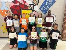 Group of children holding up certificates in front of a colorful mural.