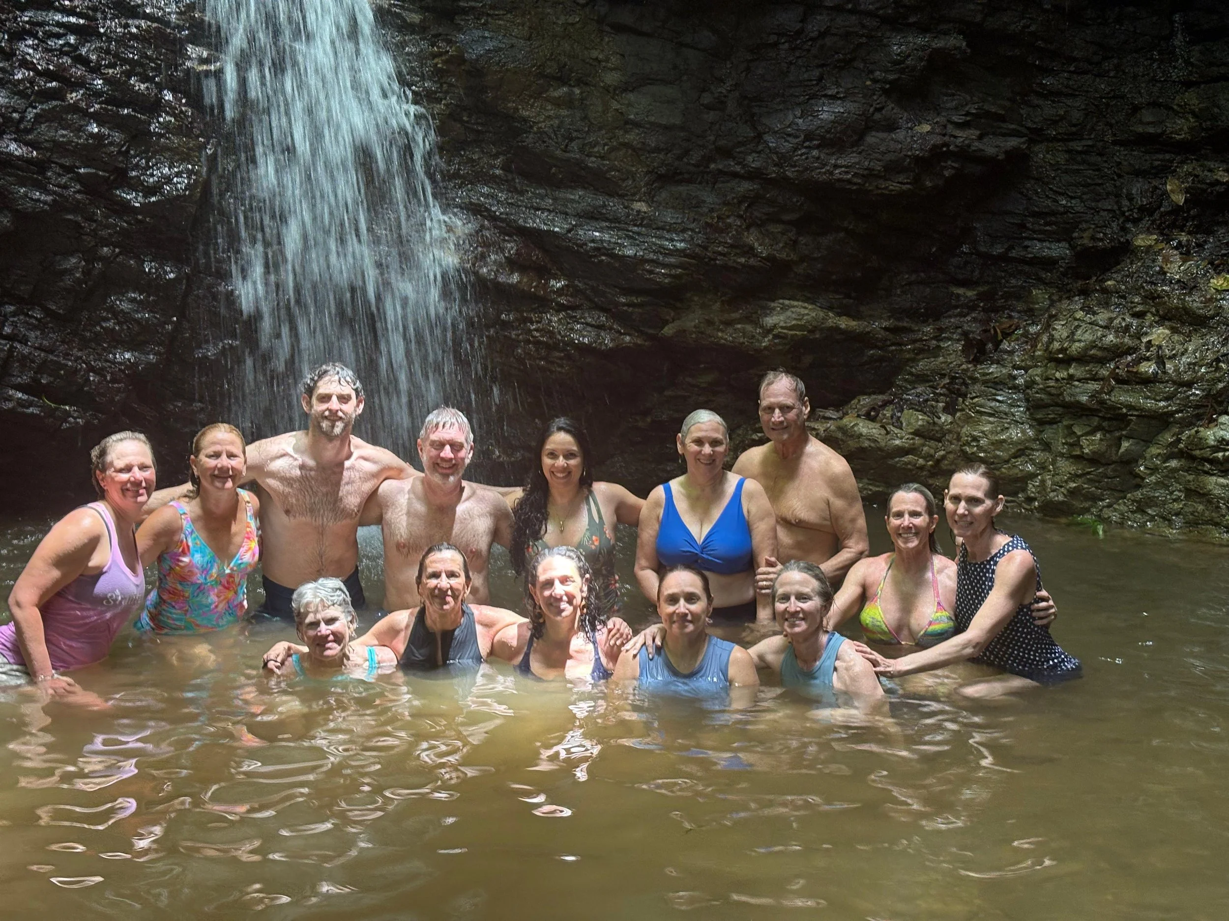 Group of people  a river or pool under a waterfall, smiling and enjoying themselves at our Costa Rica Yoga Retreat.