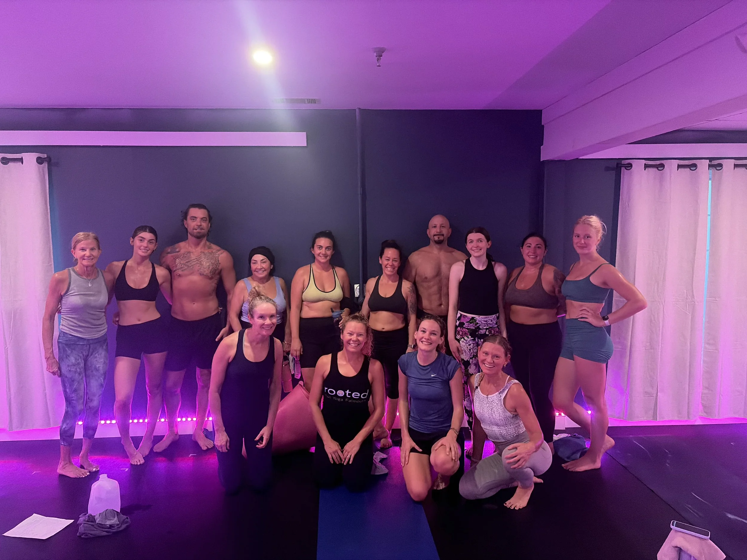 Group of people posing in a yoga or fitness studio after Inferno Hot Pilates, some standing and some kneeling, in workout attire.