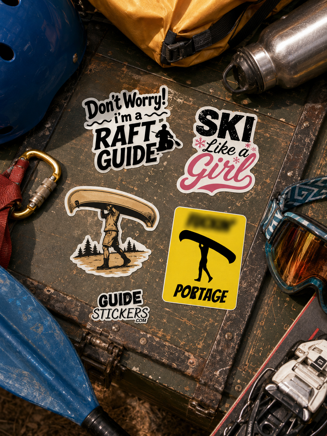 Collection of stickers related to outdoor sports on a rustic wooden surface, including a rafting guide, skiing girl, a hiker with a kayak, and a portage sign. Surrounding items include a helmet, water bottle, climbing gear, goggles, and a blue paddle.