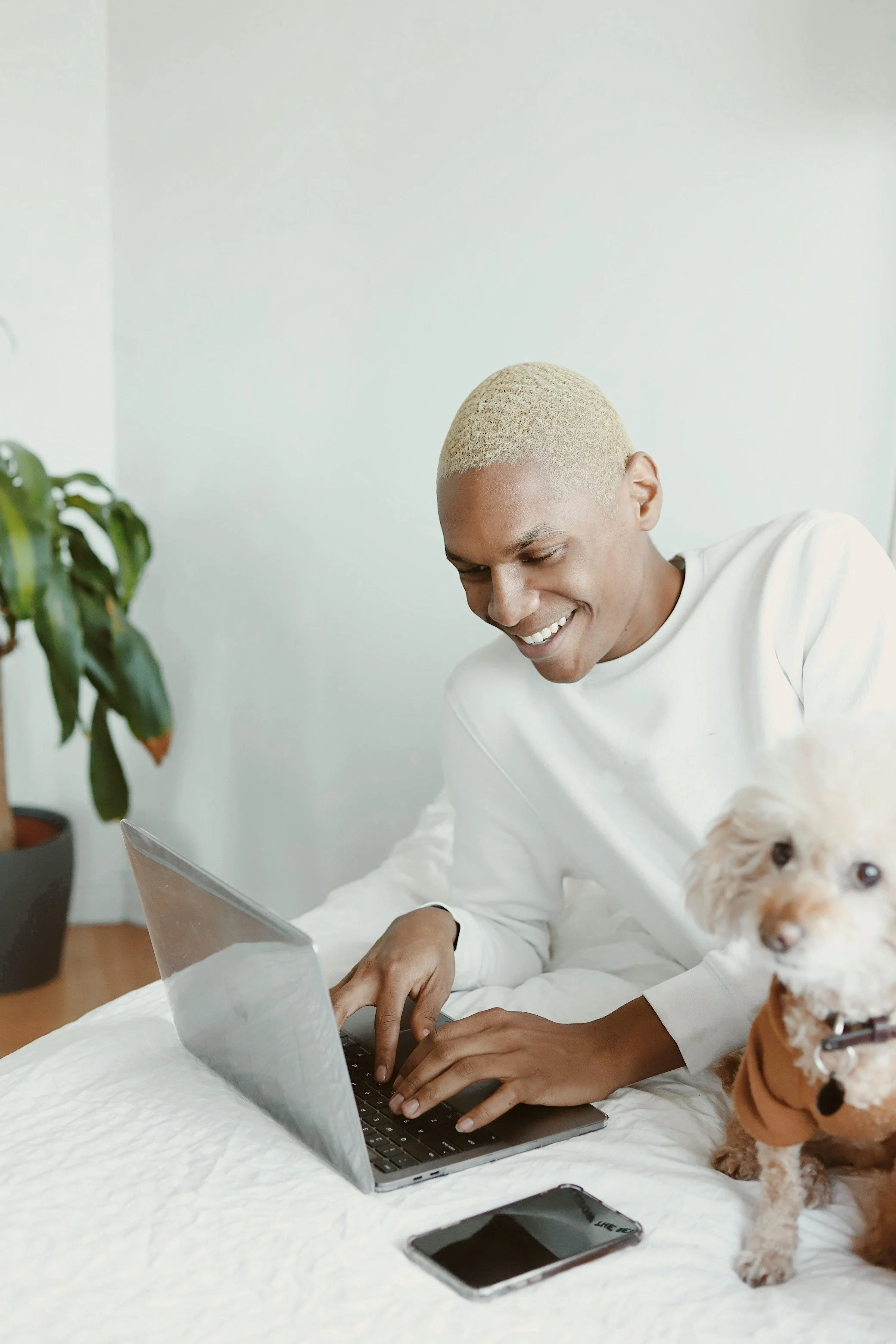 Smiling person working at a laptop with a small dog
