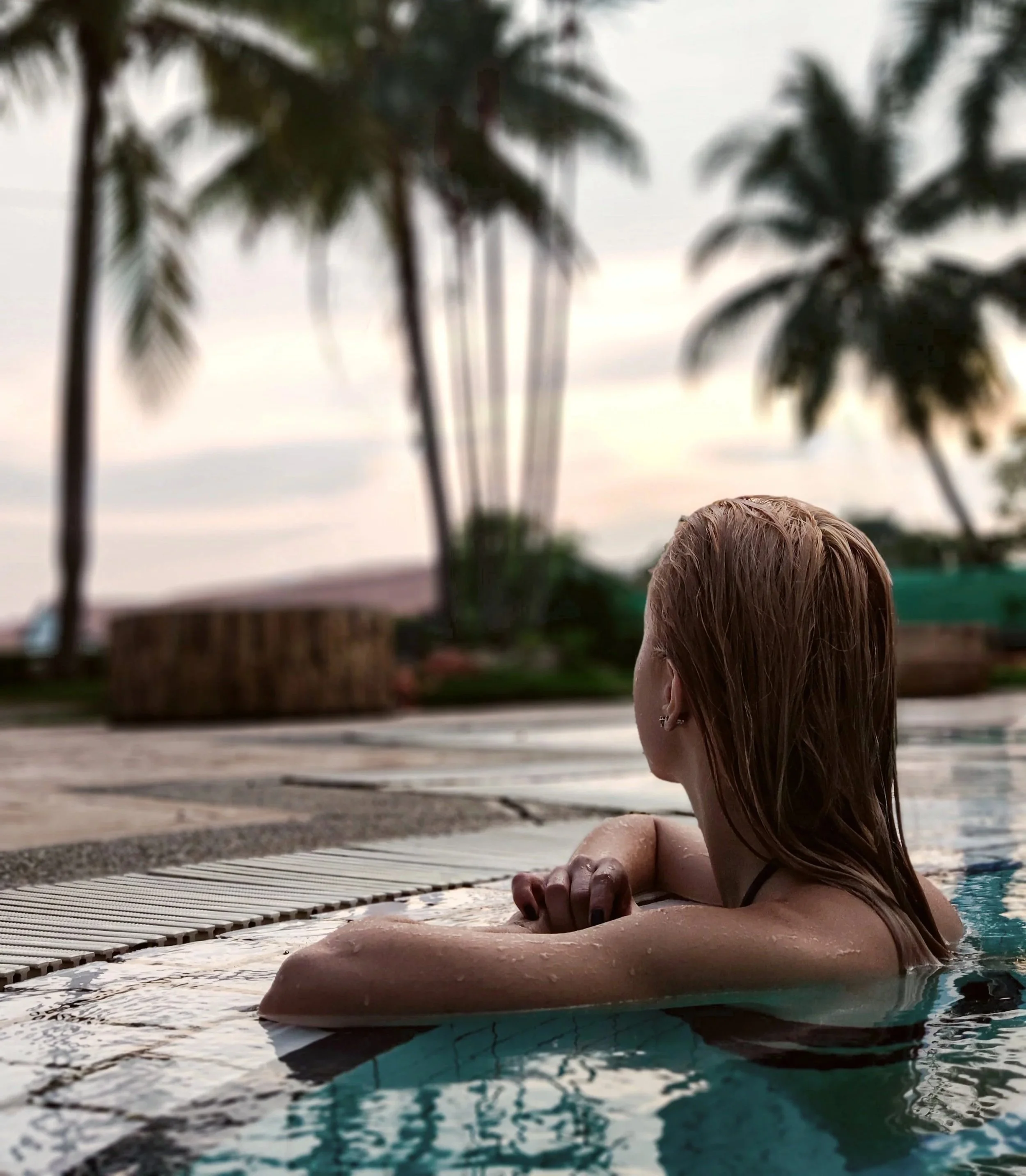 Woman relaxing in an infinity pool at sunset