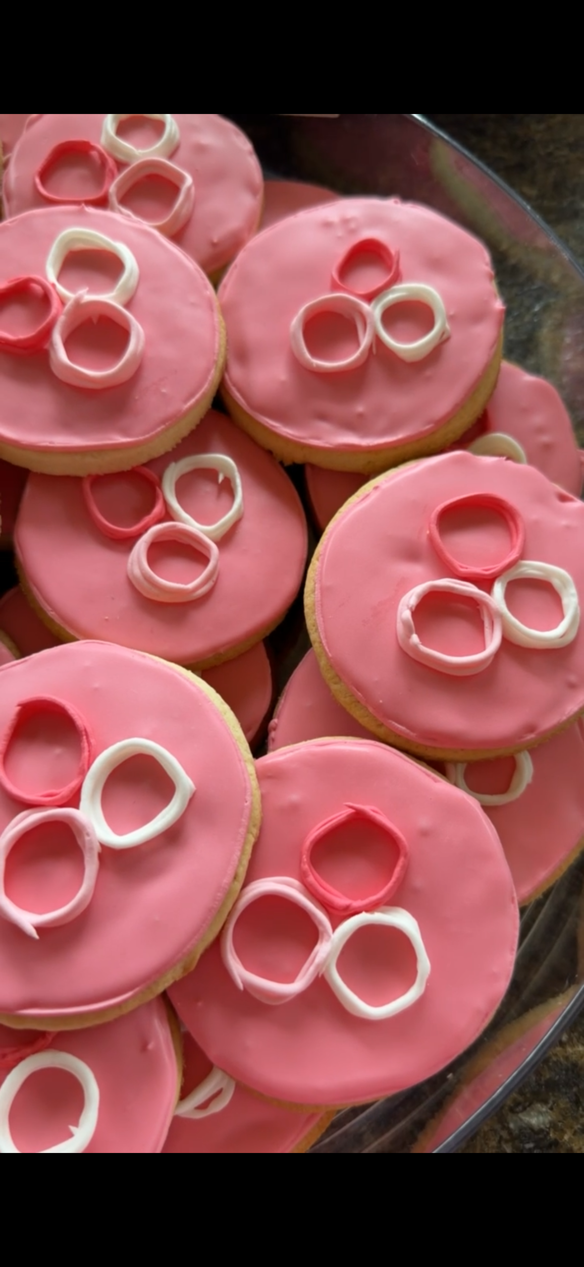 Pink frosted cookies decorated with white and pink ring-shaped candies on top.