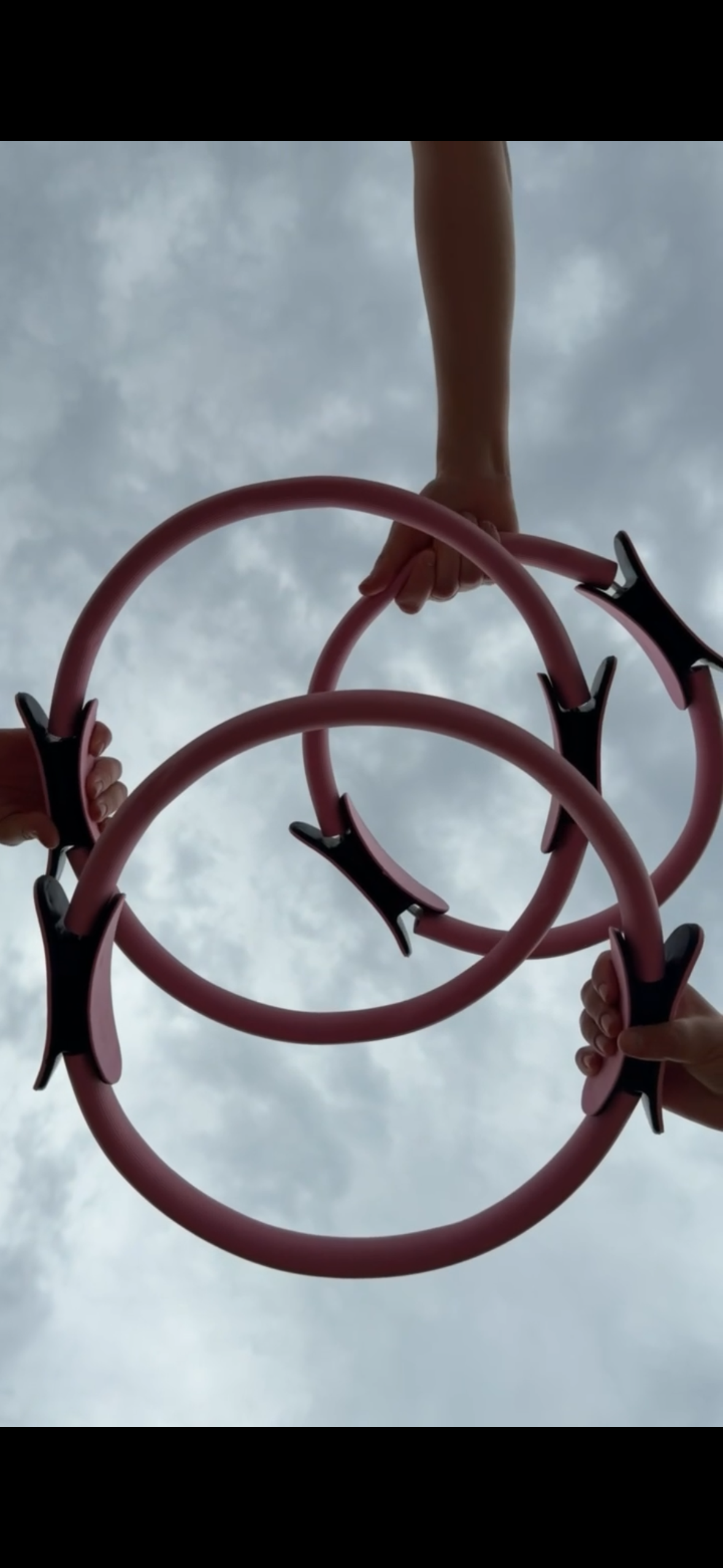 Multiple people holding pink pilates hoops.