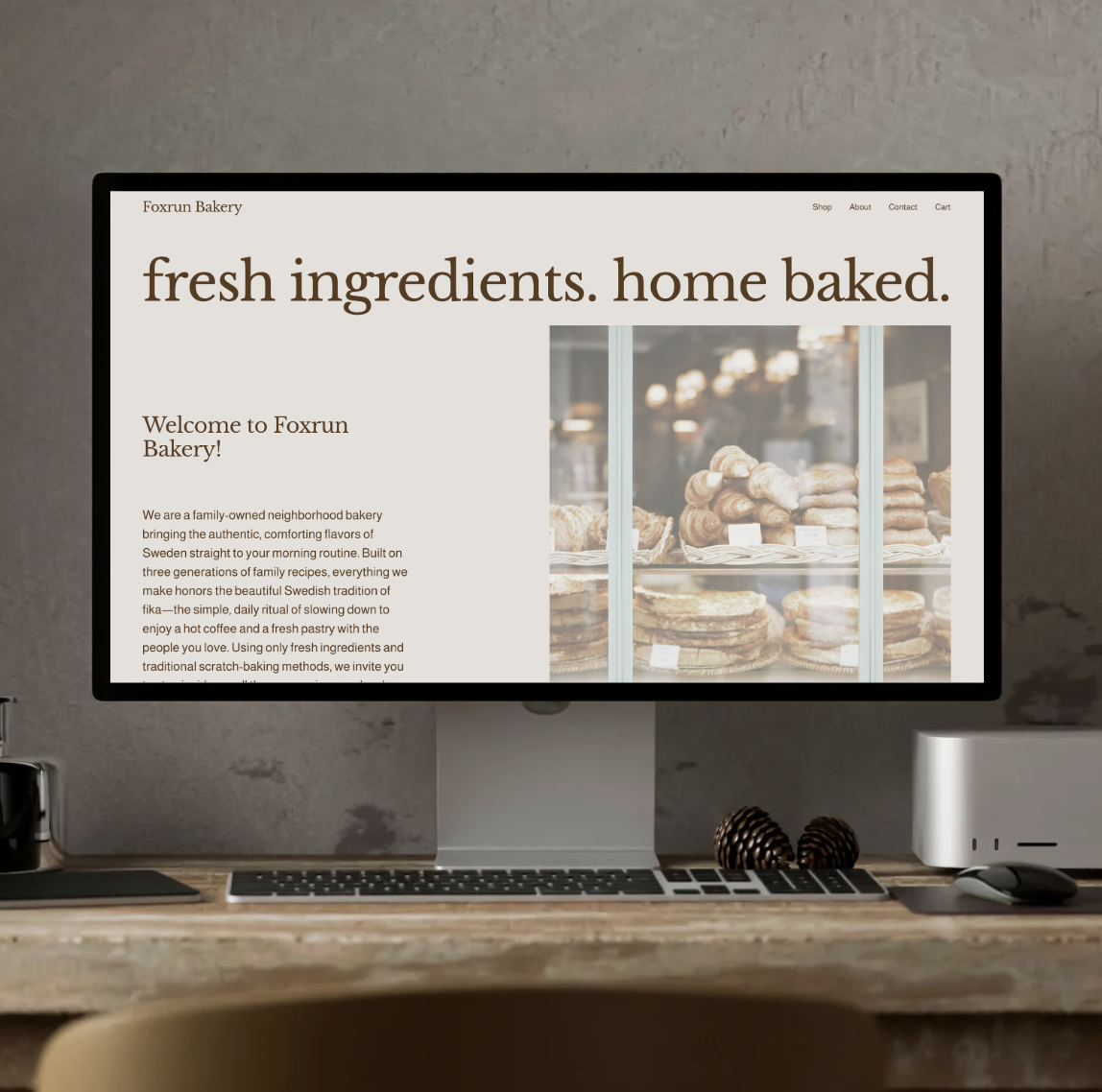 Computer monitor displaying Foxrun Bakery website, with baked goods in the background and text emphasizing fresh ingredients and home baking.