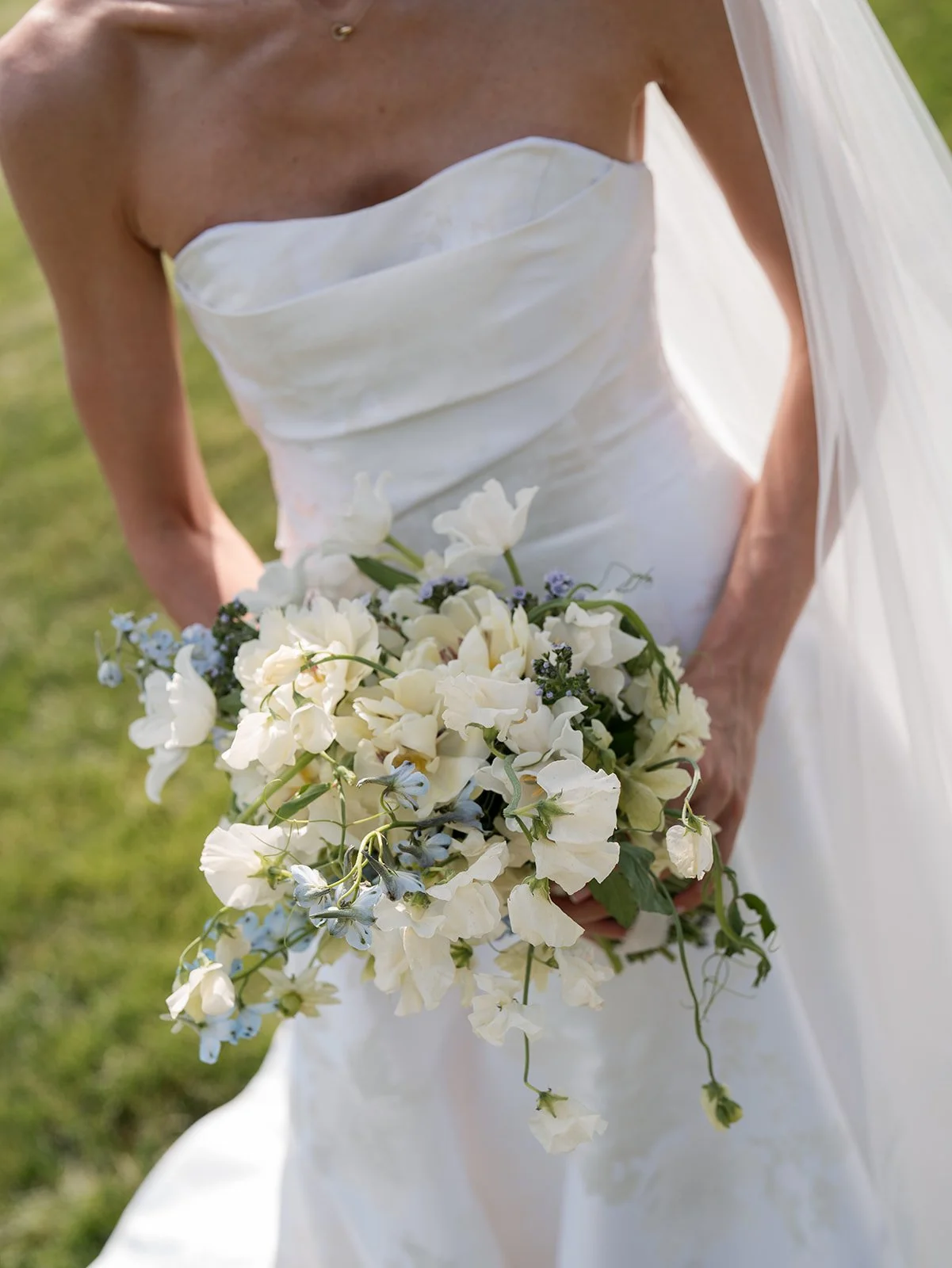 Bride holding a white bouquet at an outdoor wedding.