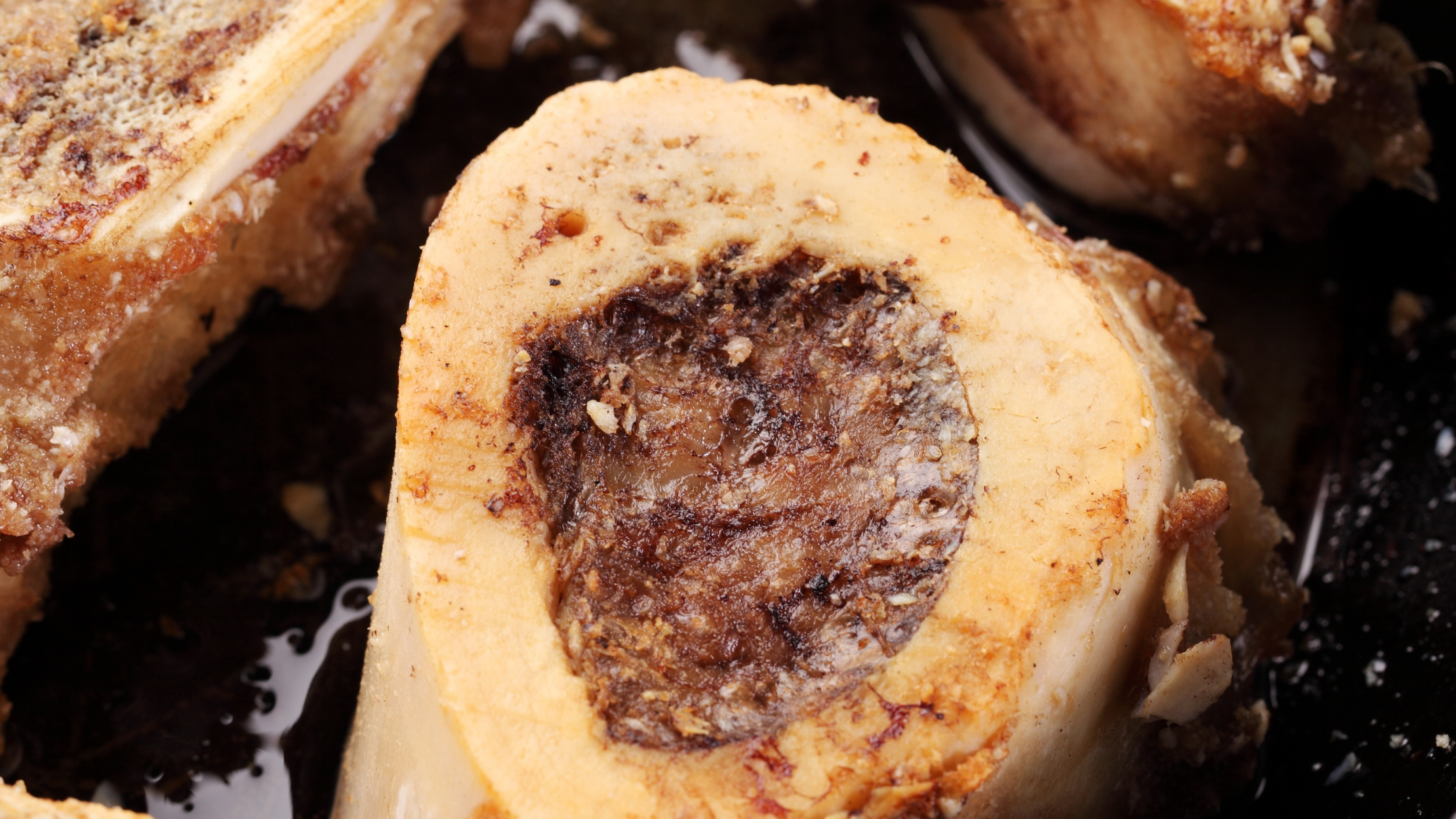 Close-up of a sliced dessert roll with a nut and fruit filling, with a dark syrup or sauce around it.