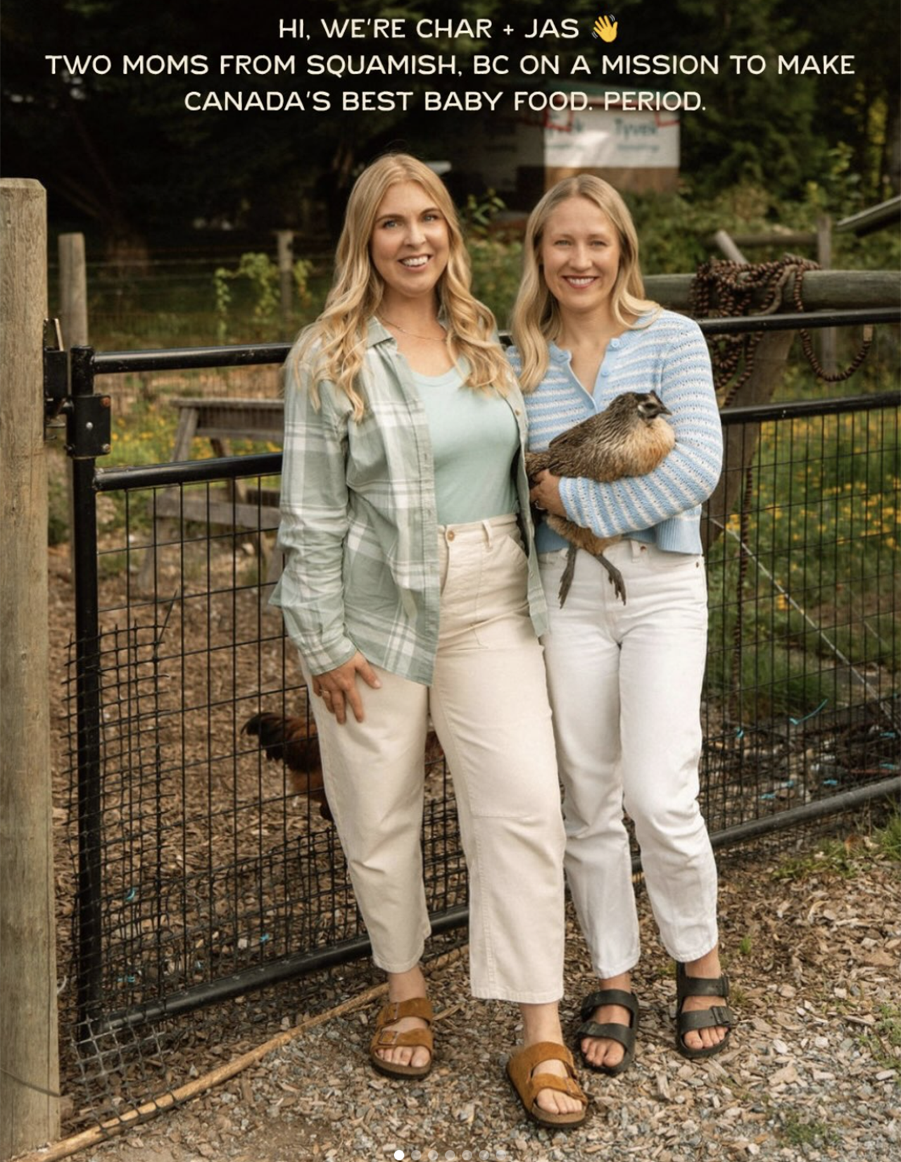 Two women standing outdoors near a fence, one holding a small bird, with trees in the background. The women are smiling and dressed casually in light-colored clothing.