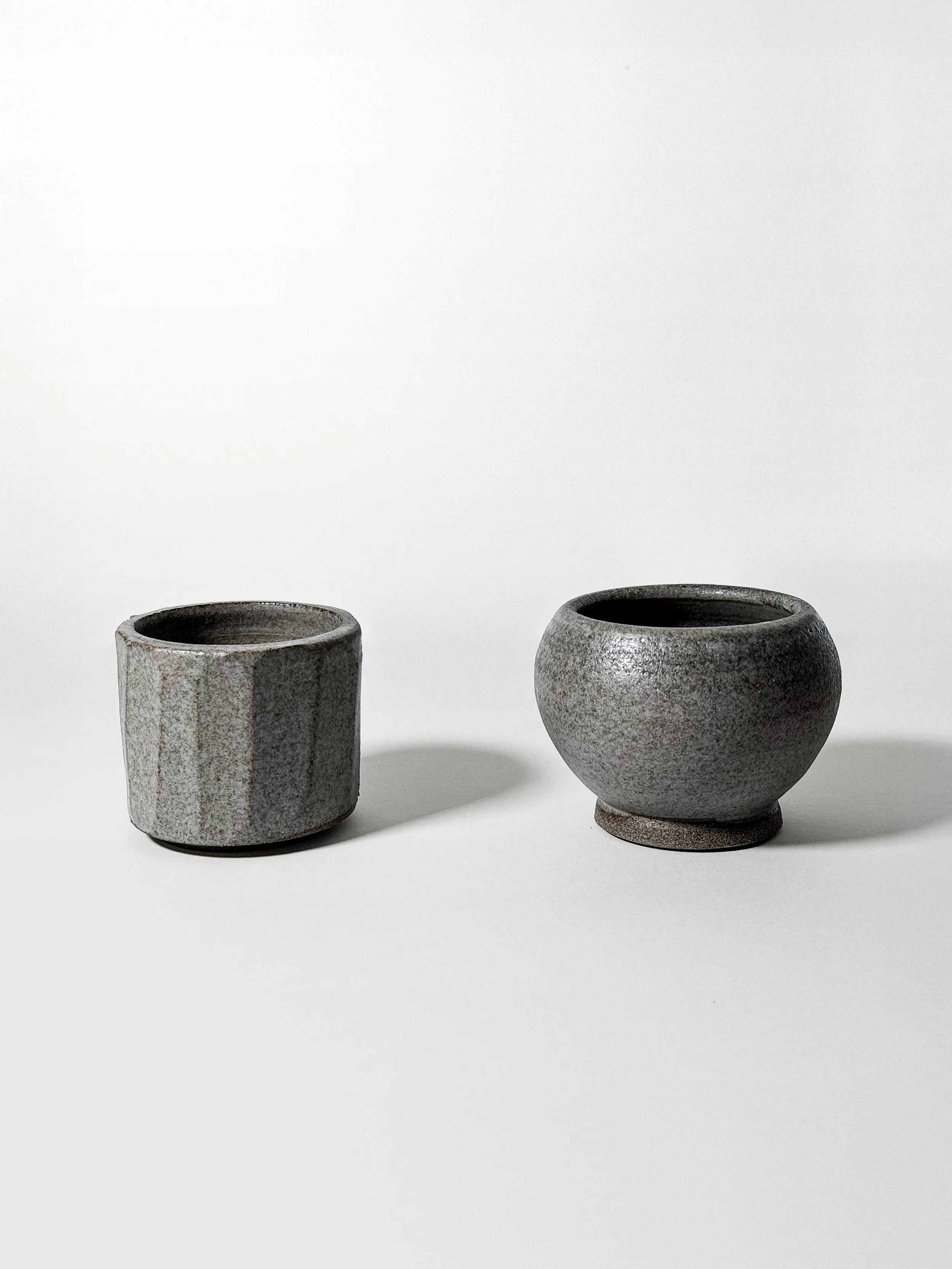close-up of two espresso trio cups showing faceted and rounded wheel-thrown stoneware forms
