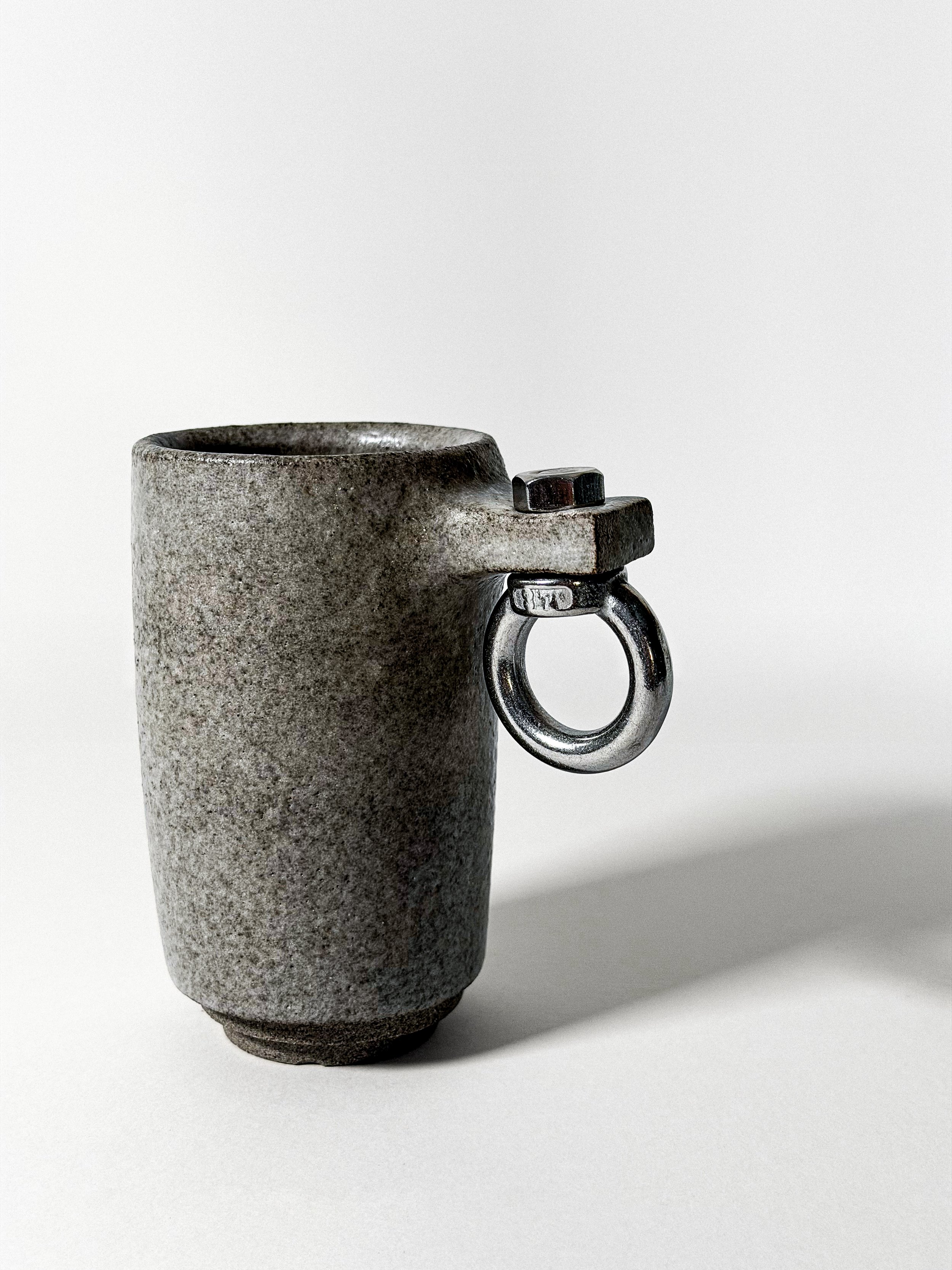 minibrut close-up of speckled stoneware texture and steel eye-bolt handle with hex nut