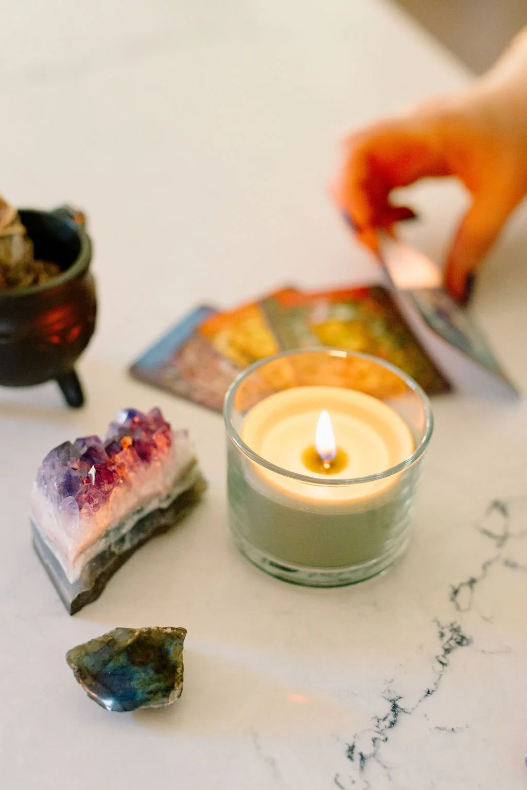 A glowing candle surrounded by colorful crystals, a small cauldron, and spiritual objects in Omy Golden's personal space.