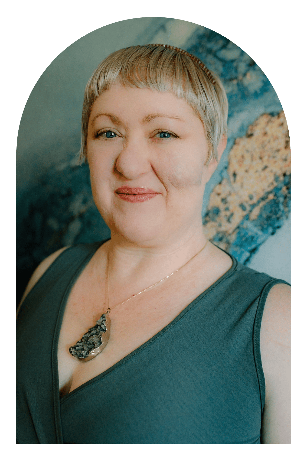 Close-up portrait of Omy Golden, therapist and founder of Dark Moon Counseling, smiling in front of a textured blue wall.