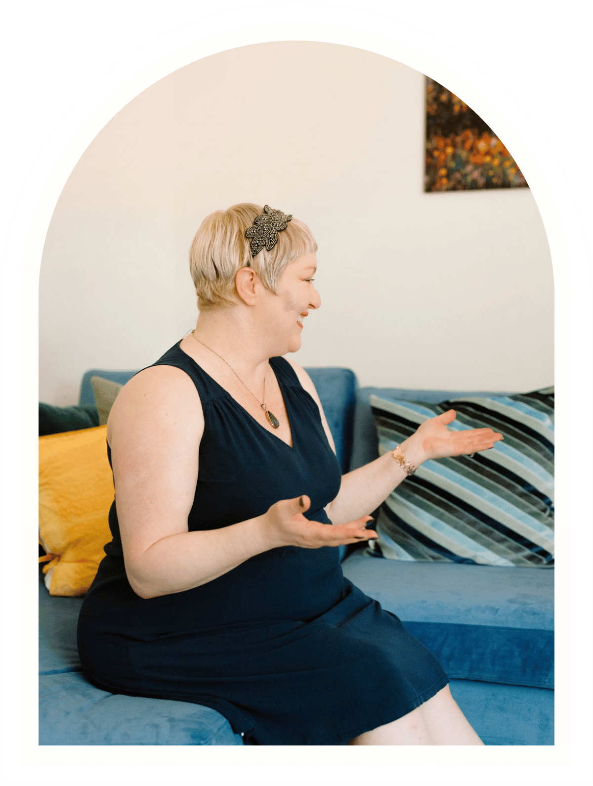 Therapist Omy Golden sitting on a blue couch during an individual therapy session