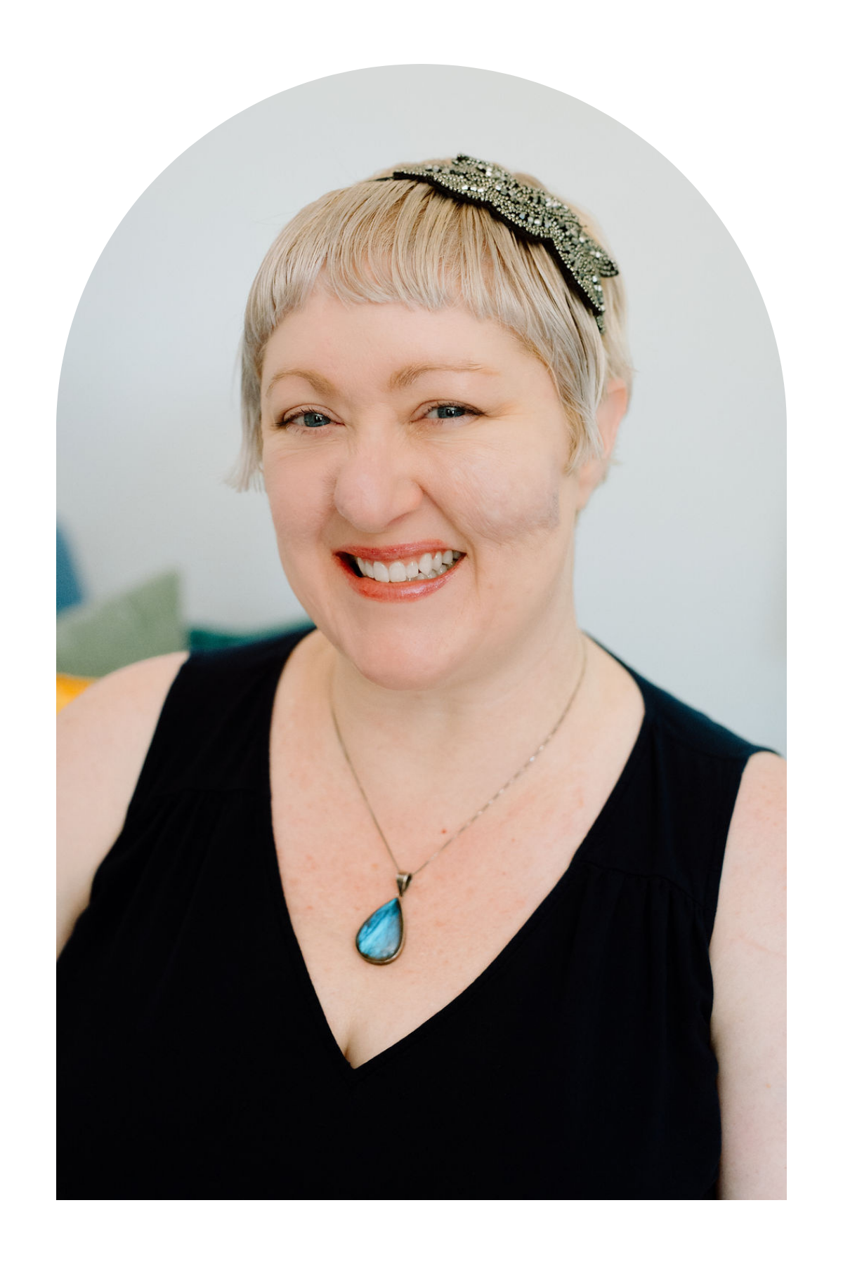Omy Golden, licensed professional counselor in Pennsylvania and Ohio, smiling in a black top with a blue pendant necklace.