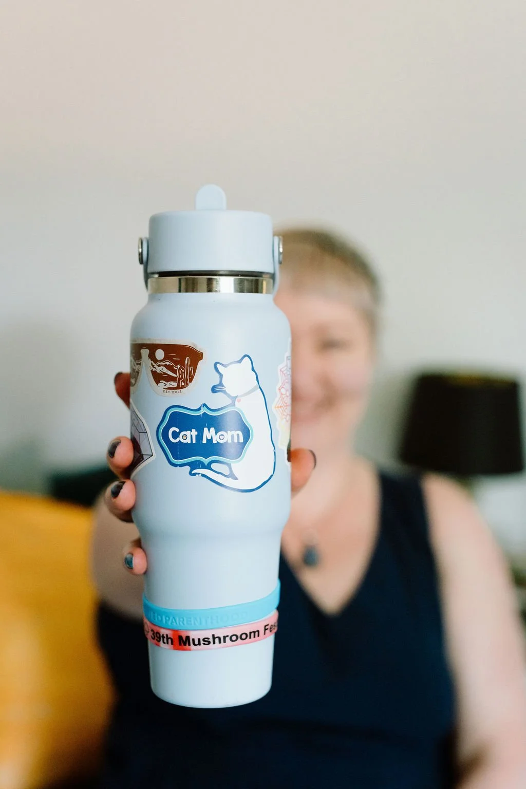 Omy Golden playfully holding a blue Cat Mom water bottle, sharing a glimpse of her personality outside the therapy room.