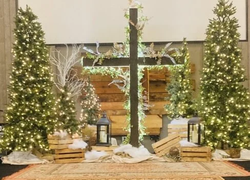 Christmas nativity scene with decorated trees, lanterns, and wooden crates.