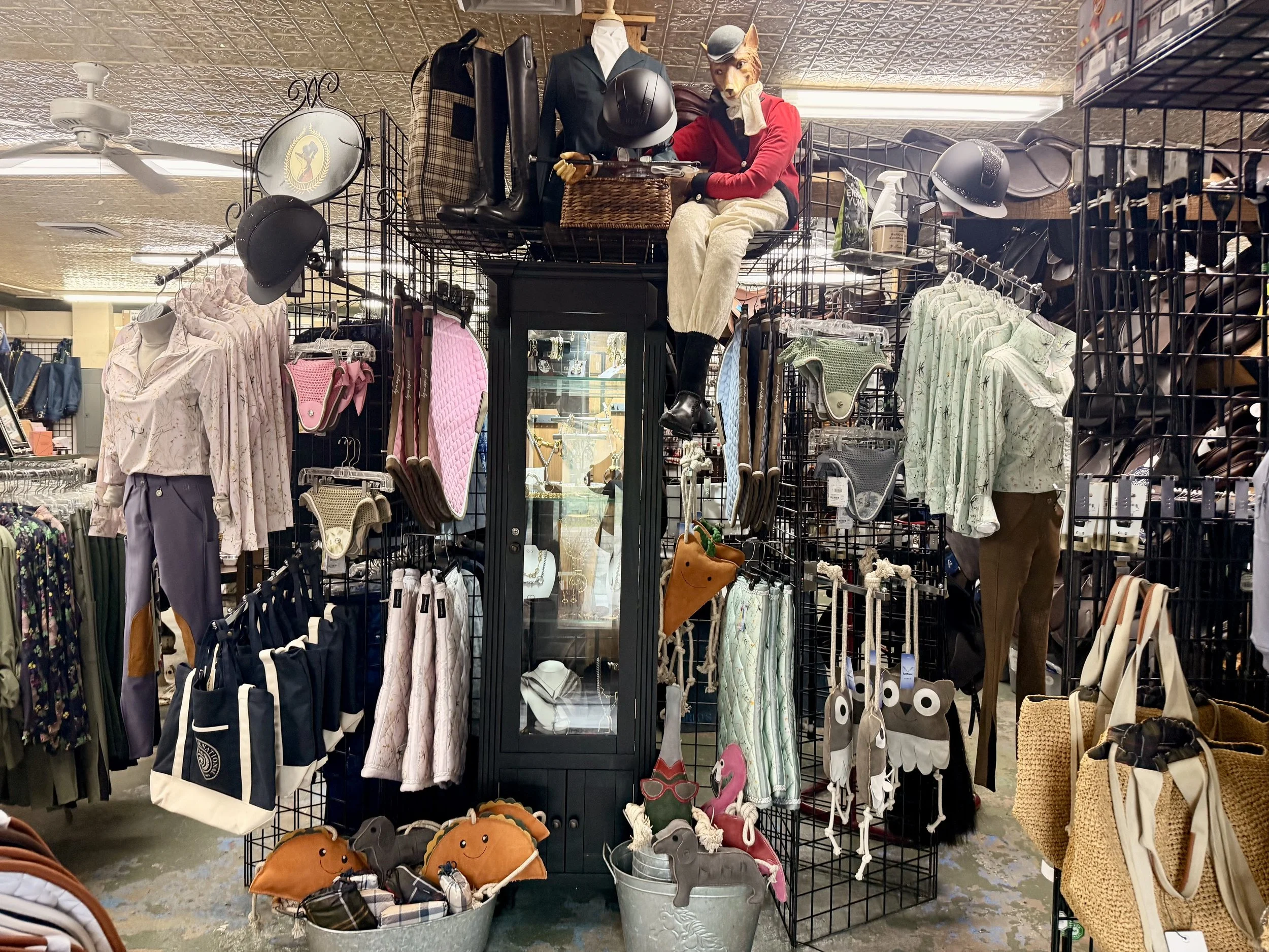 Clothing and accessories display at a thrift store, featuring jackets, bags, hats, and plush pumpkins with smiling faces.