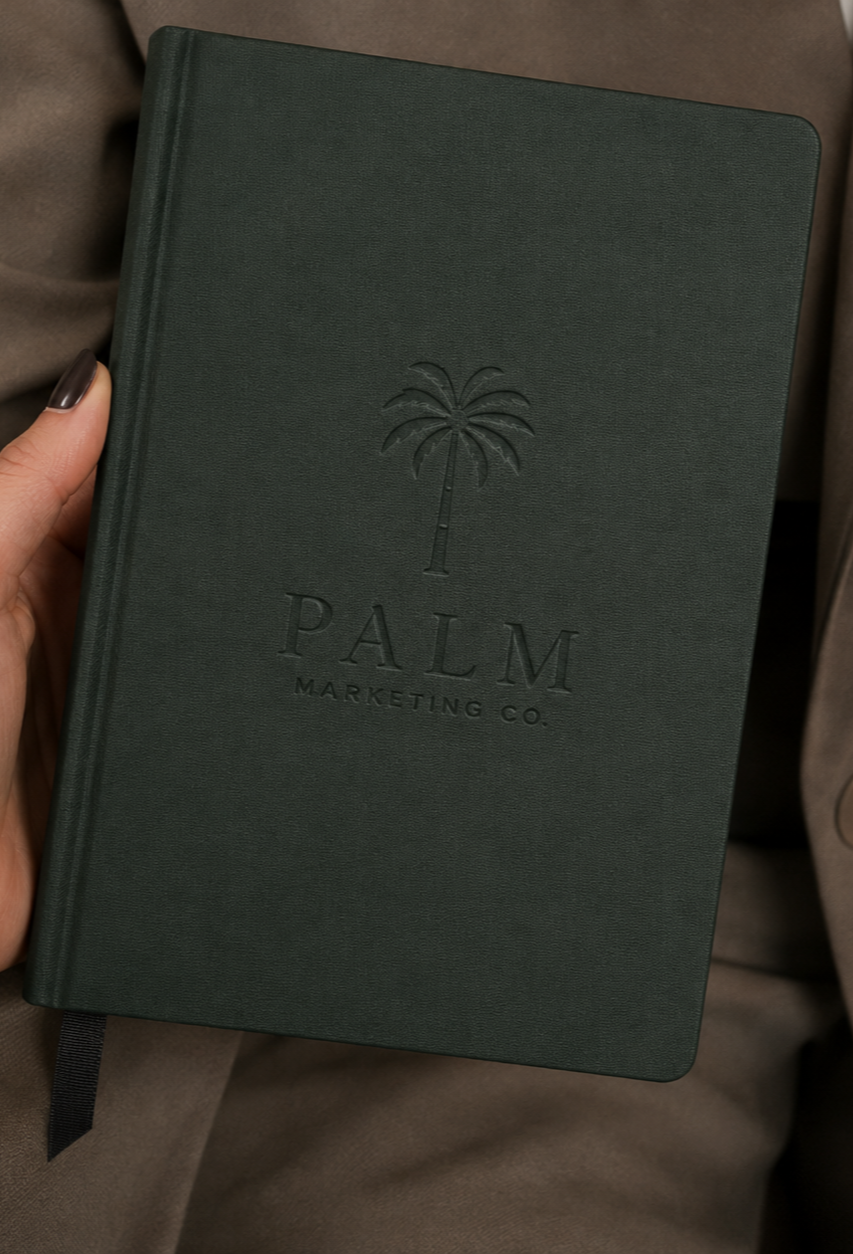 Green hardcover notebook with embossed palm tree and text reading 'PALM MARKETING CO.'.