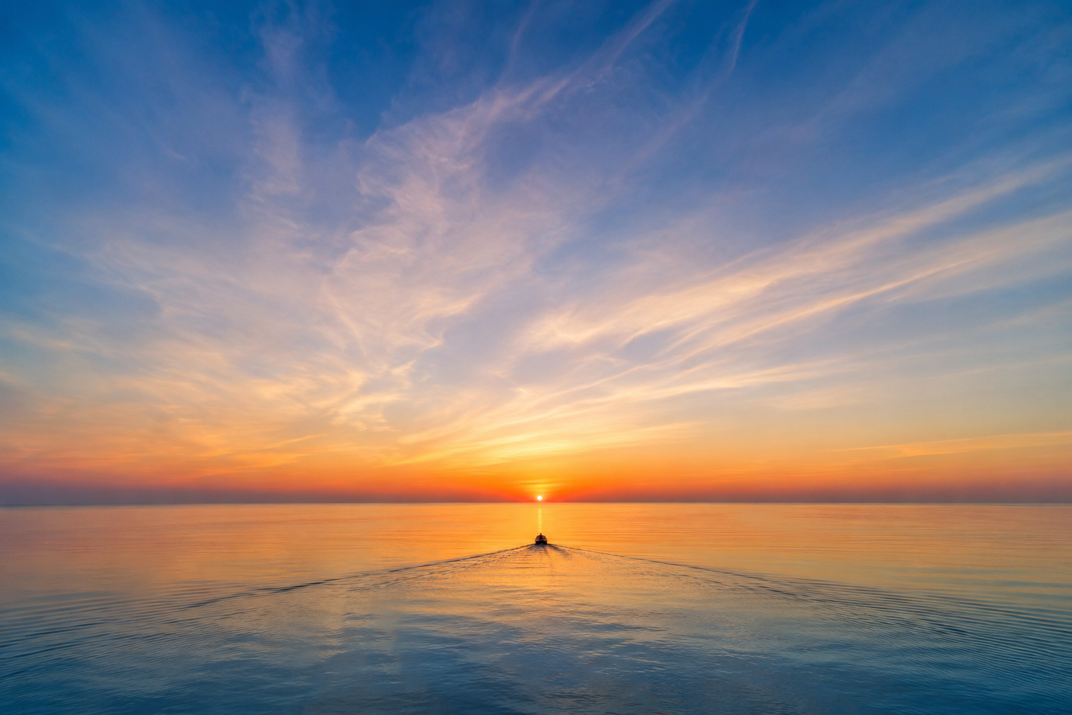 A boat sailing on calm ocean waters during a sunset, with colorful clouds in the sky and the sun near the horizon.