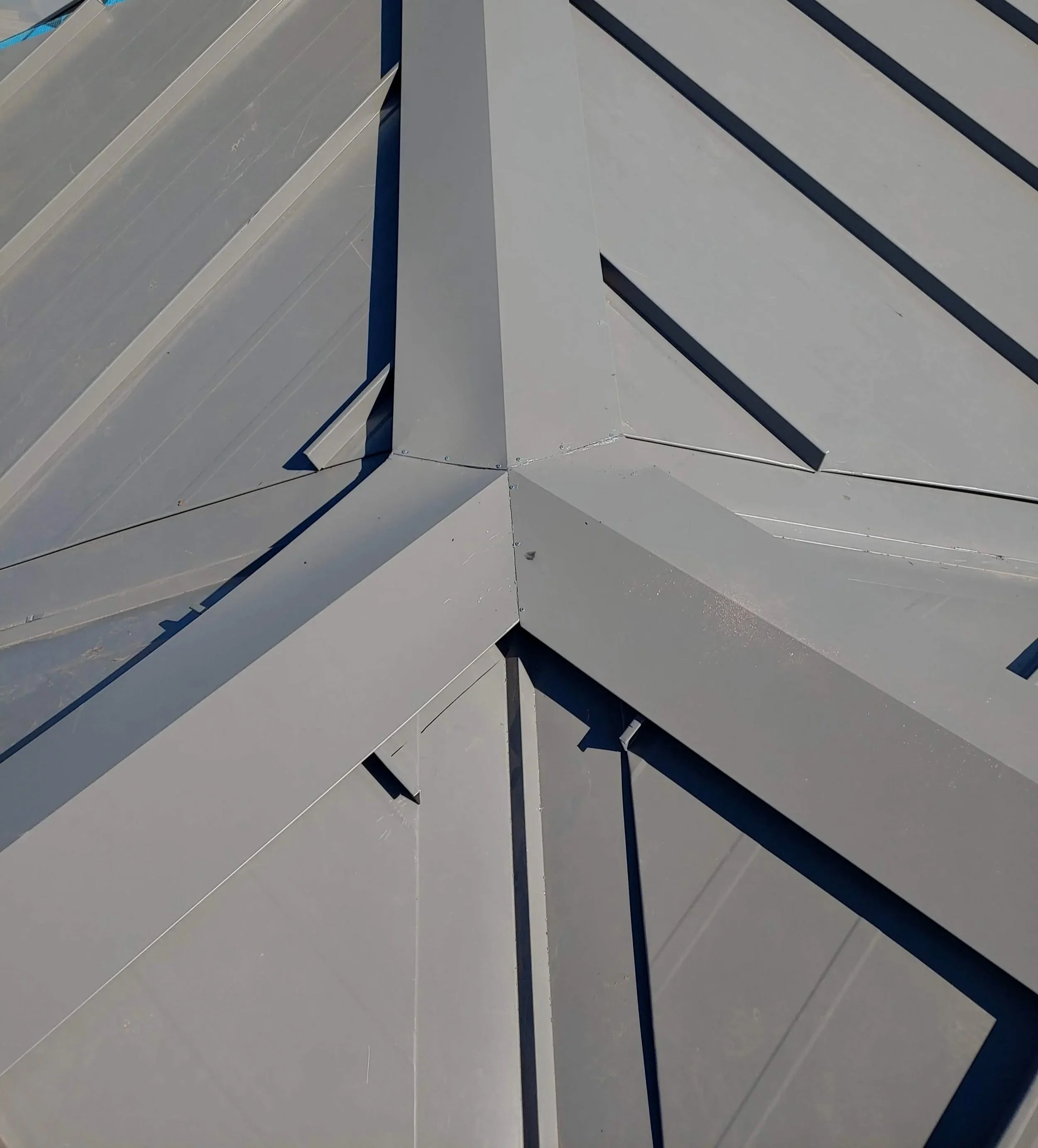 Close-up of a rooftop with prominent strobe vents or exhaust vents and ridges, painted in shades of gray and blue.
