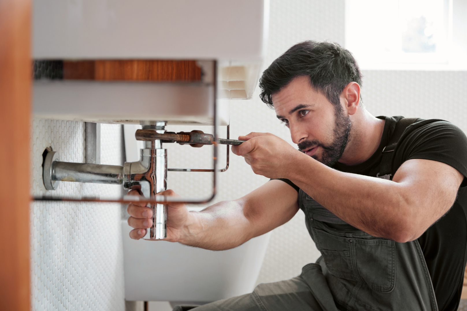 Mobile maintenance worker completing plumbing repair by fixing a sink