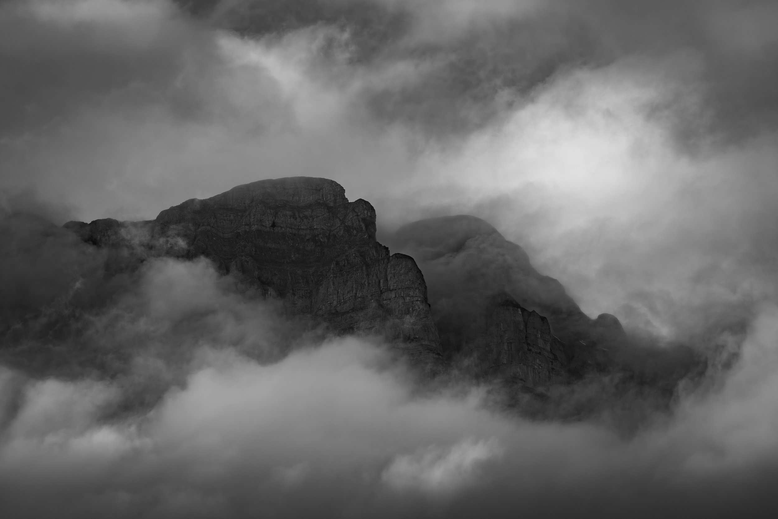 Dramatische Schwarz-Weiss-Landschaftsaufnahme einer Bergkulisse mit markanten Wolkenformationen
