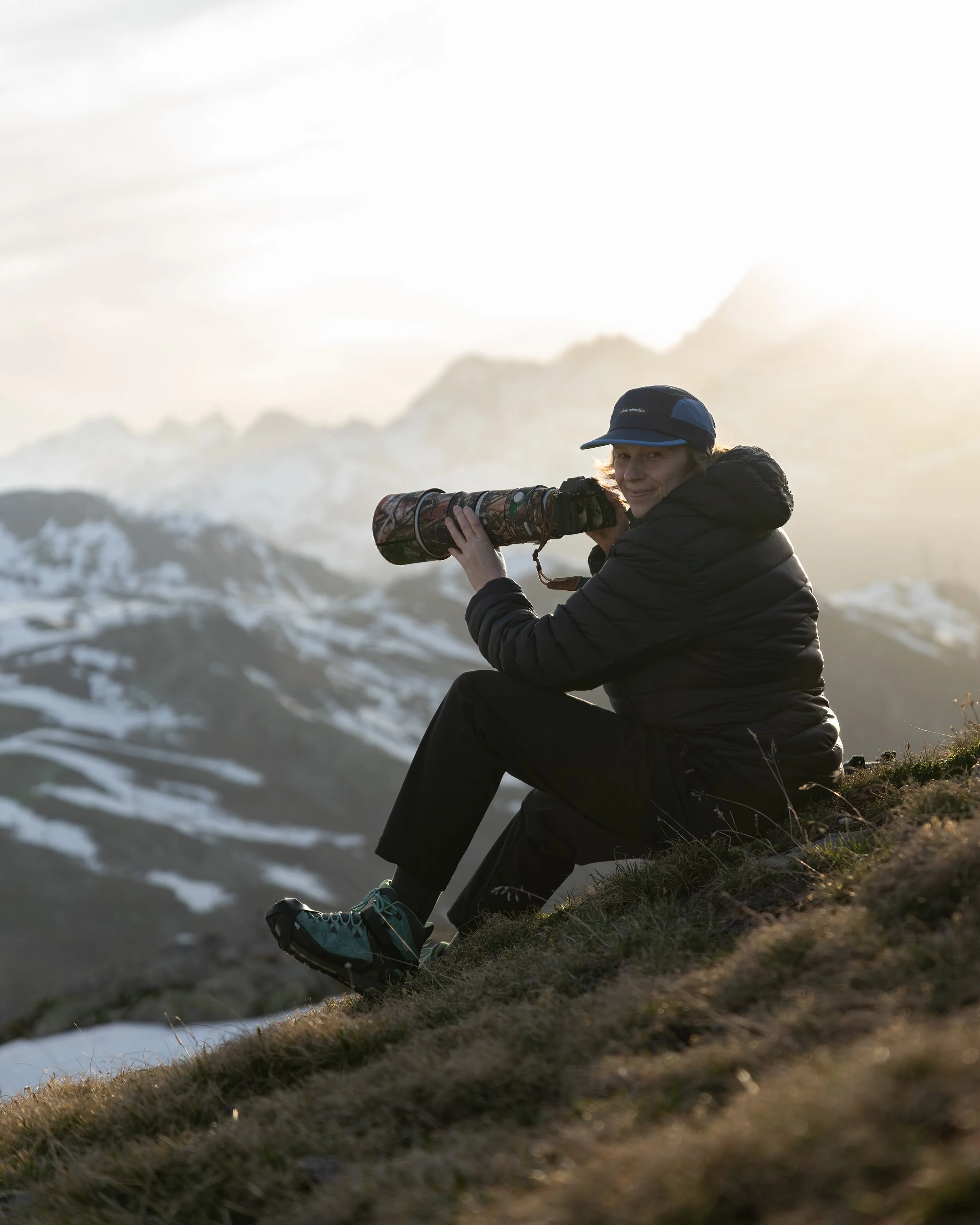Wildlife-Fotografin Ariane Totzke mit Teleobjektiv in den Walliser Alpen während einer Fotosession in den Schweizer Bergen bei Sonnenuntergang
