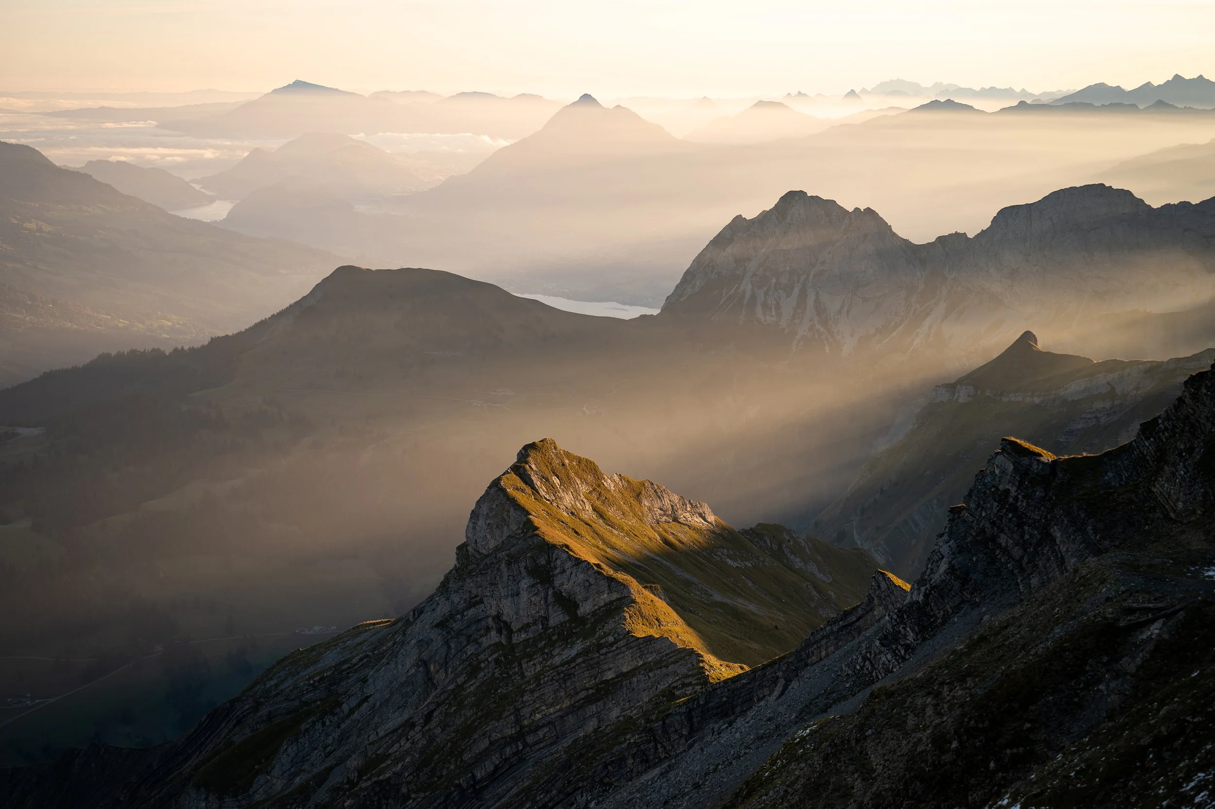 Goldenes Morgenlicht über dem Brienzer Rothorn mit Sonnenstrahlen, Berggipfeln und Nebel in den Schweizer Alpen