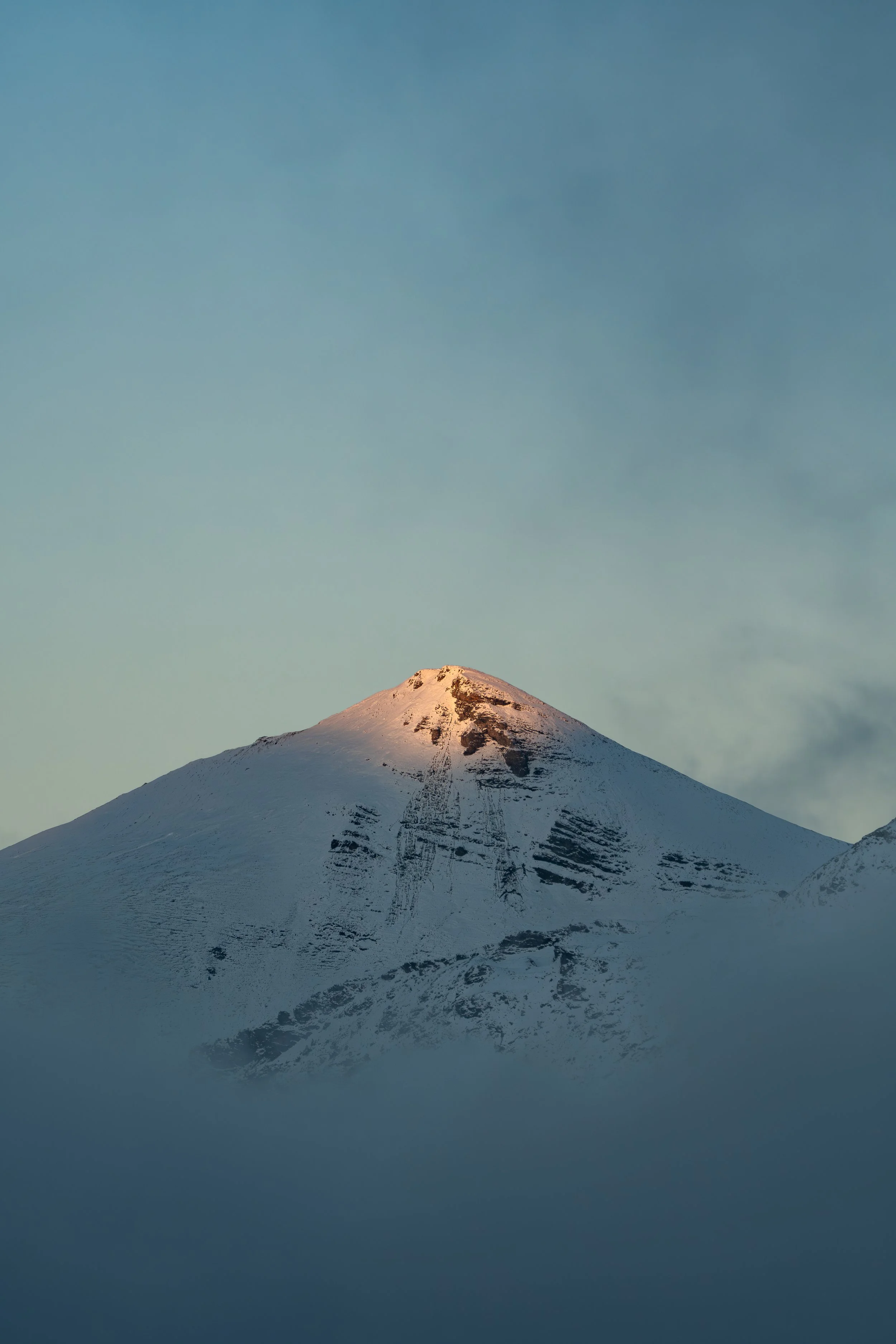 Letzte Sonnenstrahlen tauchen eine schneebedeckte Bergspitze in den Schweizer Alpen in goldenes Licht