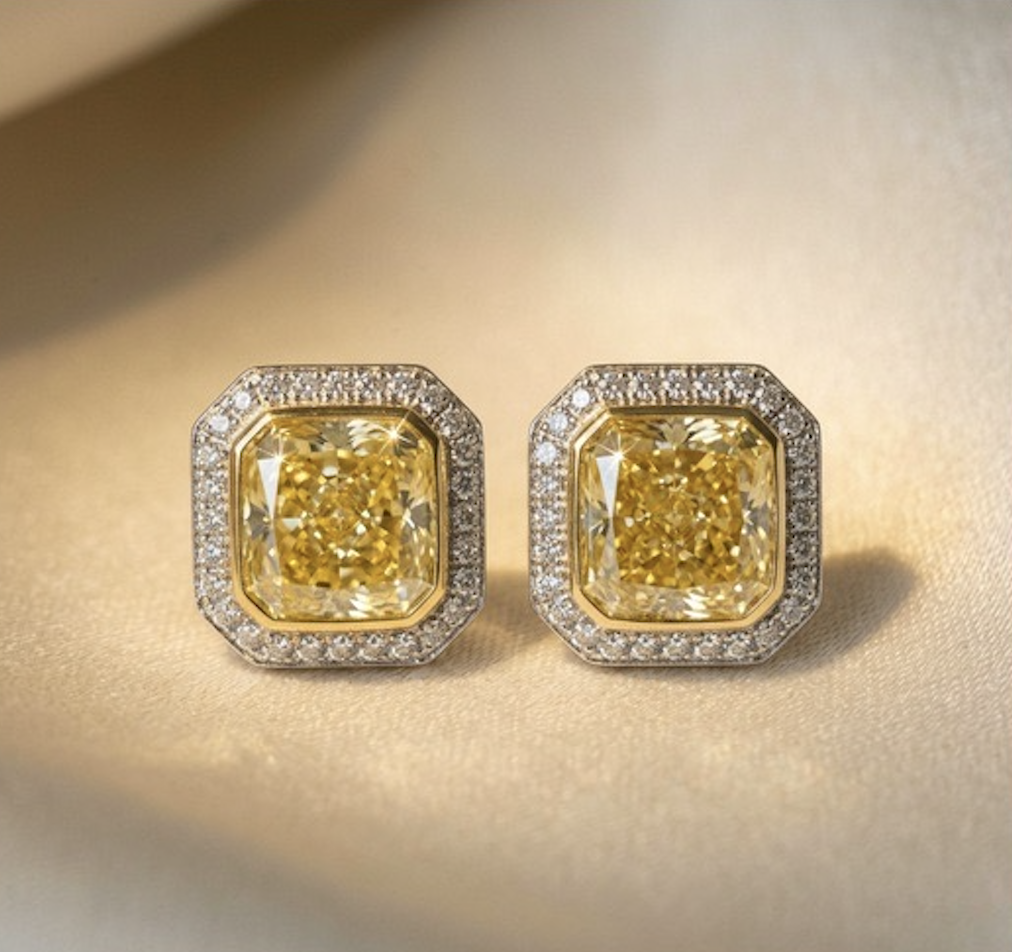 Pair of square yellow gemstone earrings surrounded by small diamonds on a gold background.
