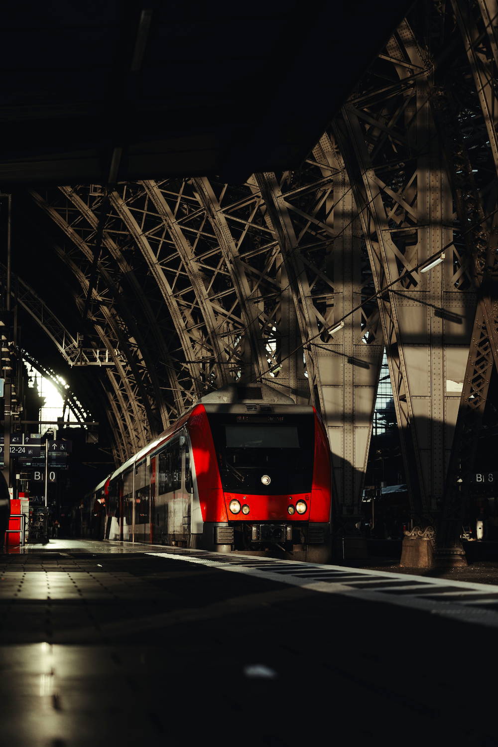 Passenger train arriving at a station beneath steel arched roof beams