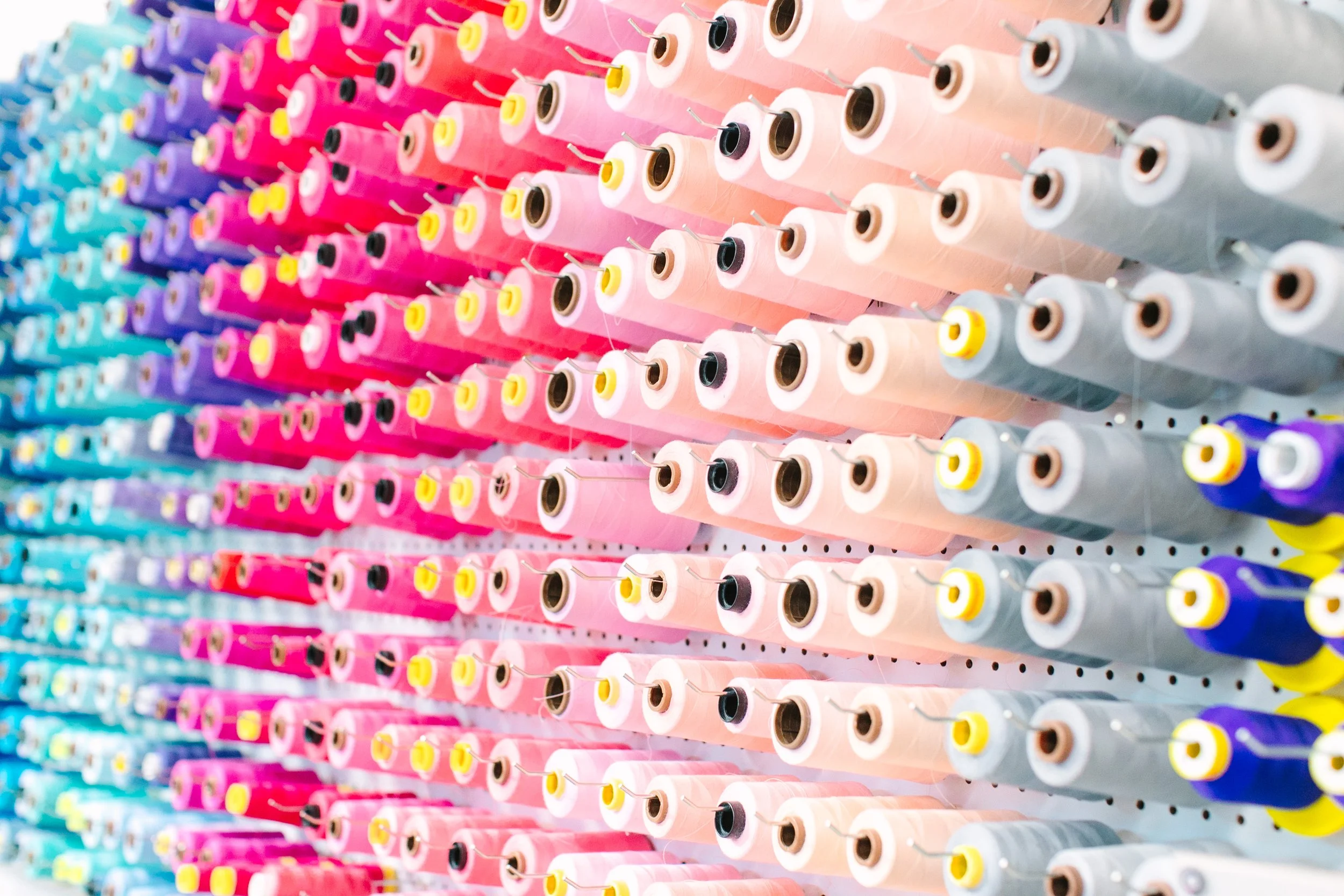 Colorful spools of thread arranged in rows on a display wall.