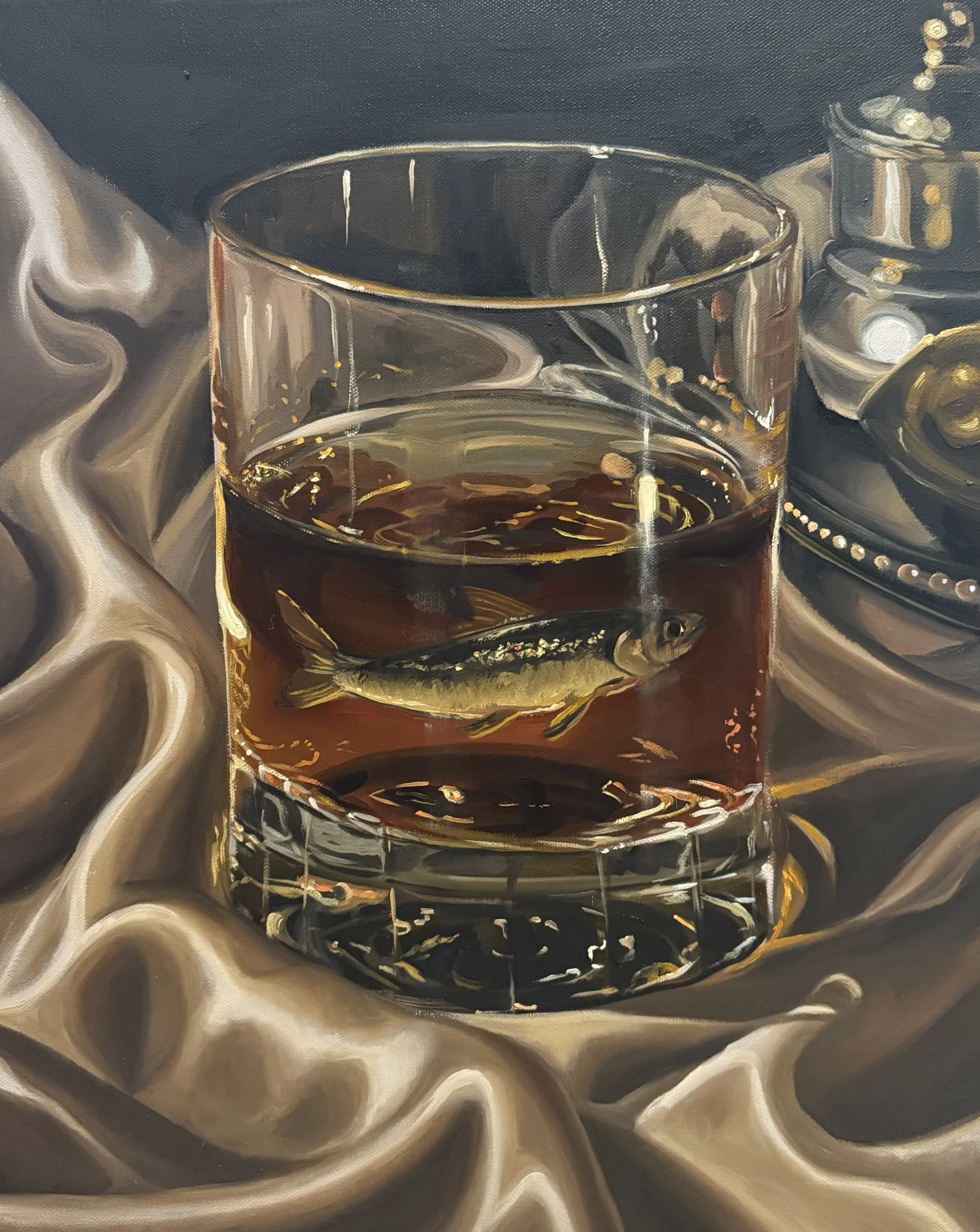 A still life painting featuring a glass of dark liquid, a small fish underneath, and a metallic object on a shiny, swirling fabric background.