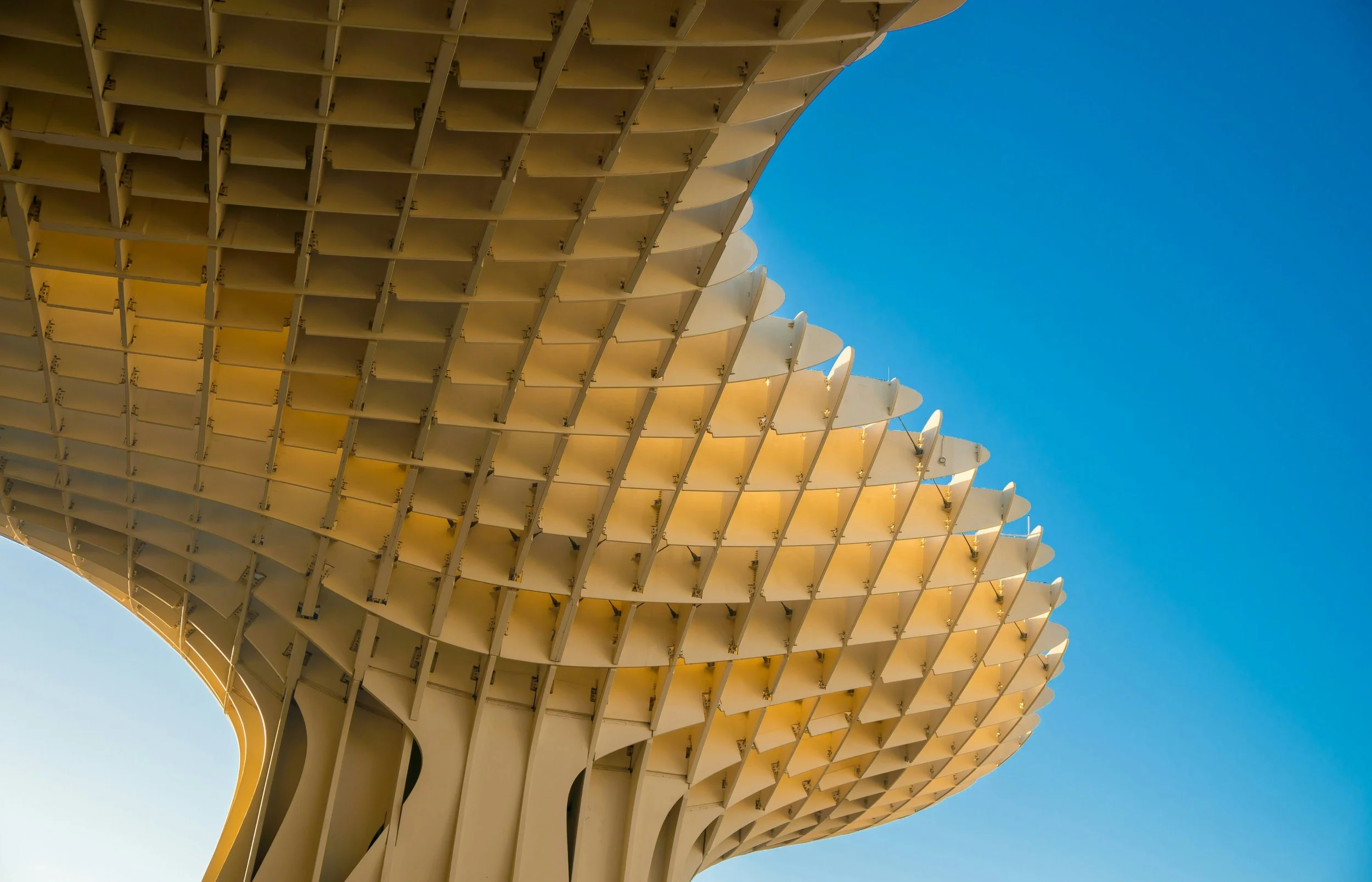 Close-up of a modern architectural structure with curved, layered, white panels against a clear blue sky.