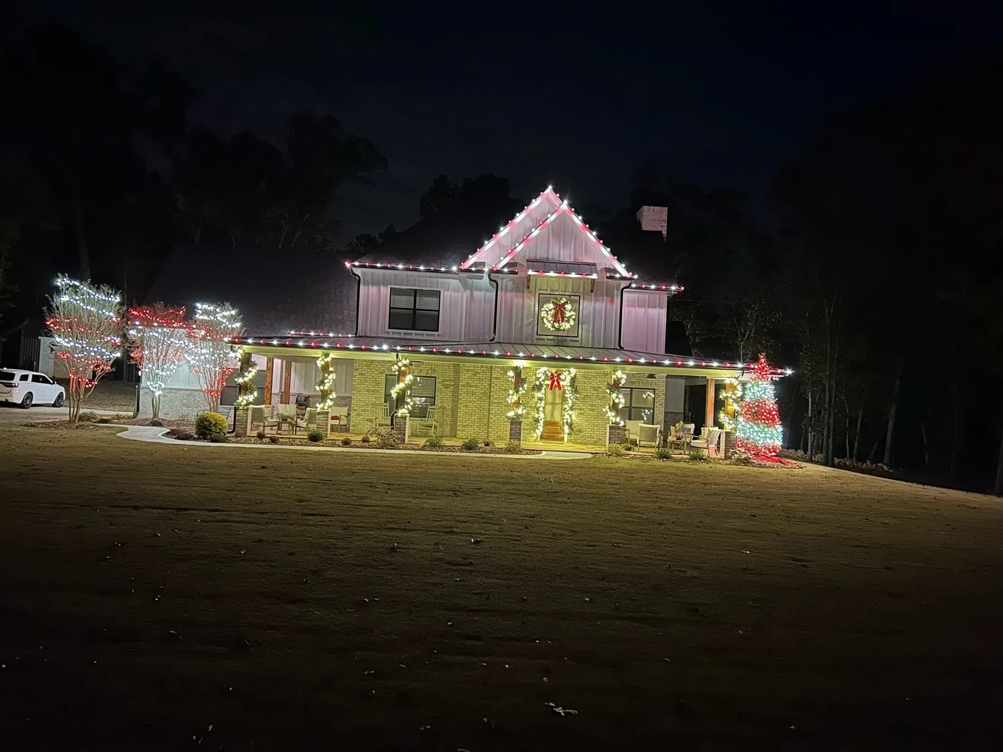 A house decorated with Christmas lights and wreaths at night.