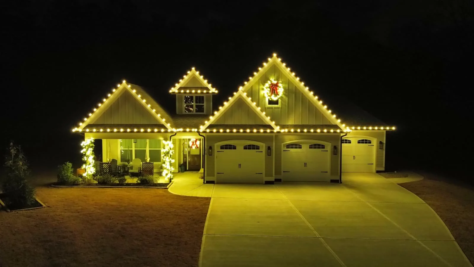 A house decorated with Christmas lights and wreaths at night.