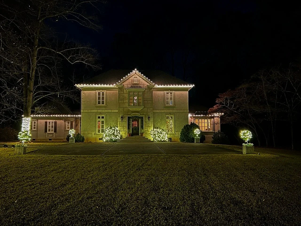 Pre-lit holiday wreath and lit garland installed on a grand entryway porch in Macon, GA.