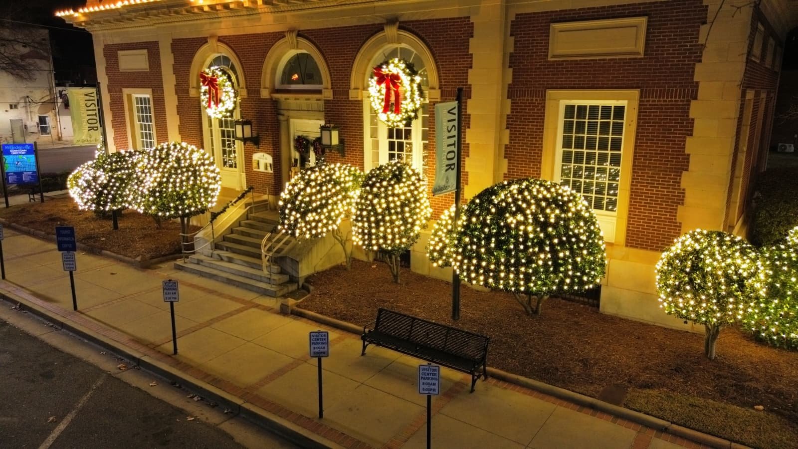 Professional Christmas lighting and pre-lit commercial wreaths on an office building in Milledgeville, Georgia.