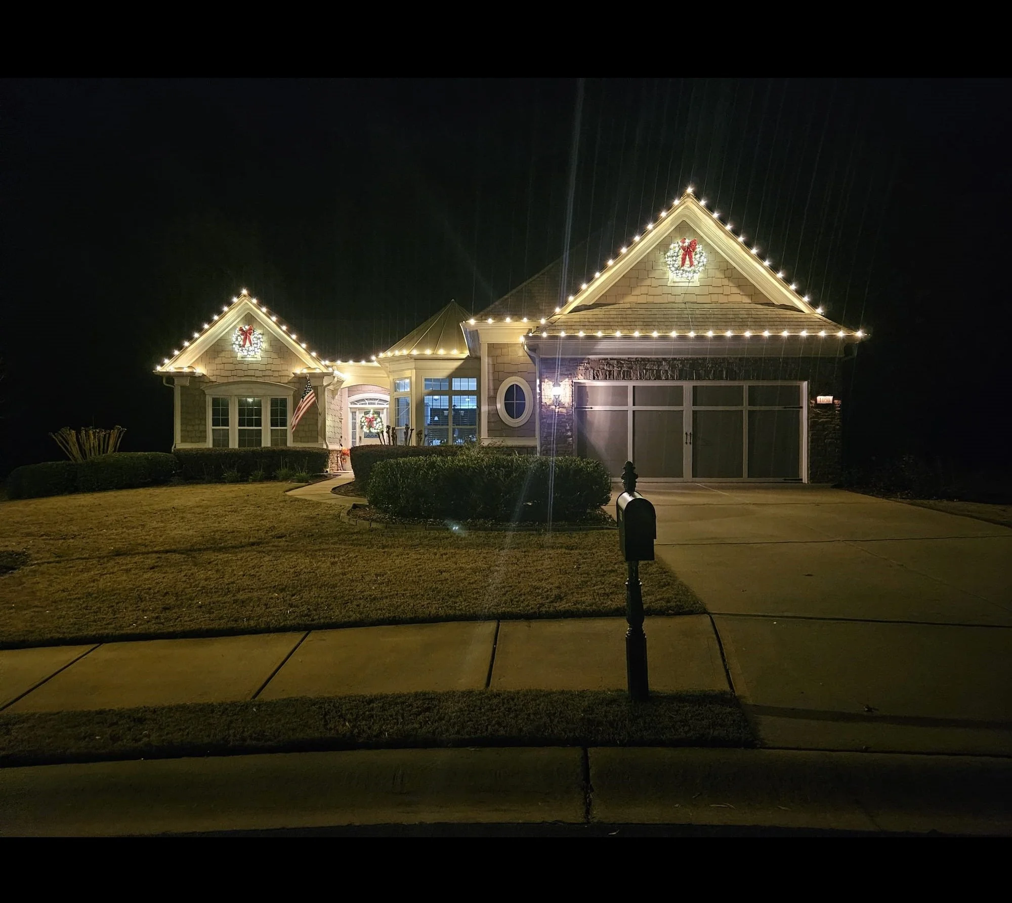 A house decorated with holiday lights and wreaths at night.
